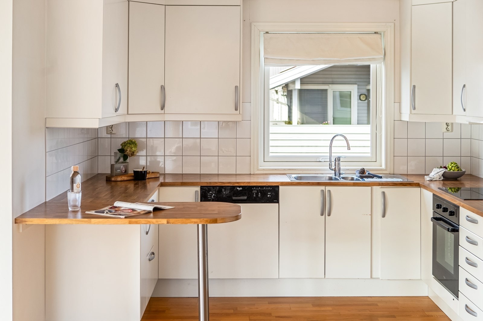 Kjøkkenet er åpent mot stuen og fremstår lyst og funksjonelt, med slette fronter og laminat benkeplater i matchende utførelse. Galleribilde