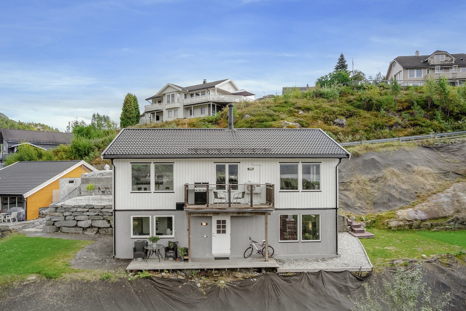 Tomta er i overkant av 1000 kvm og er opparbeida med støttemurar i stein og betong, gruslagt tun og to plenar Galleribilde