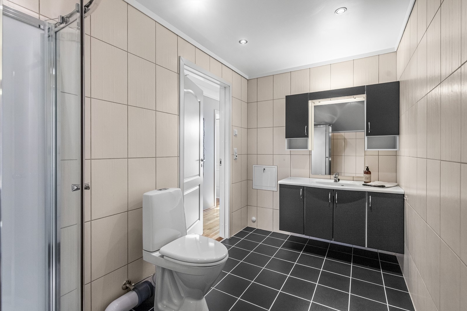 Pent og delikat baderom med varmekabler i gulvet. Baderommet er utstyrt med et nyere dusjkabinett og nyere gulvmontert toalett. Videre er det en praktisk baderomsinnredning med overhengt speil og skap. Galleribilde