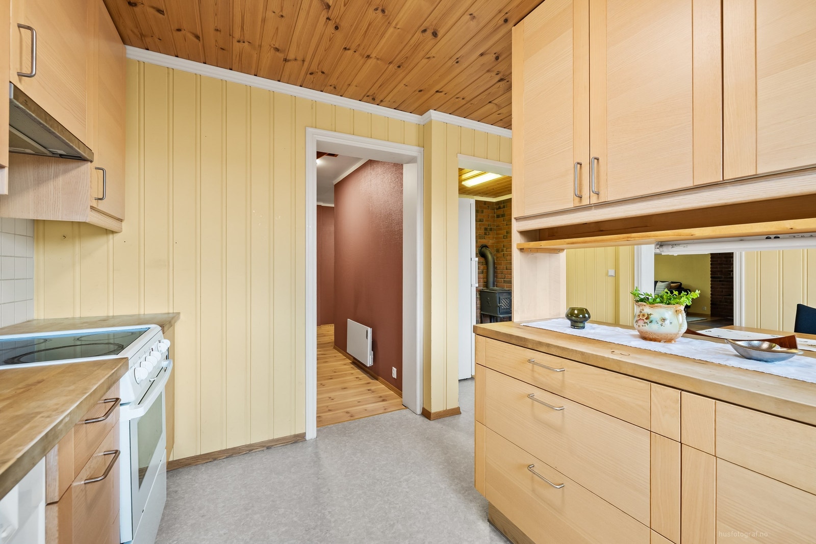 Flislagt felt på vegg over benkeplate av heltre og lysarmaturer under overskap Galleribilde