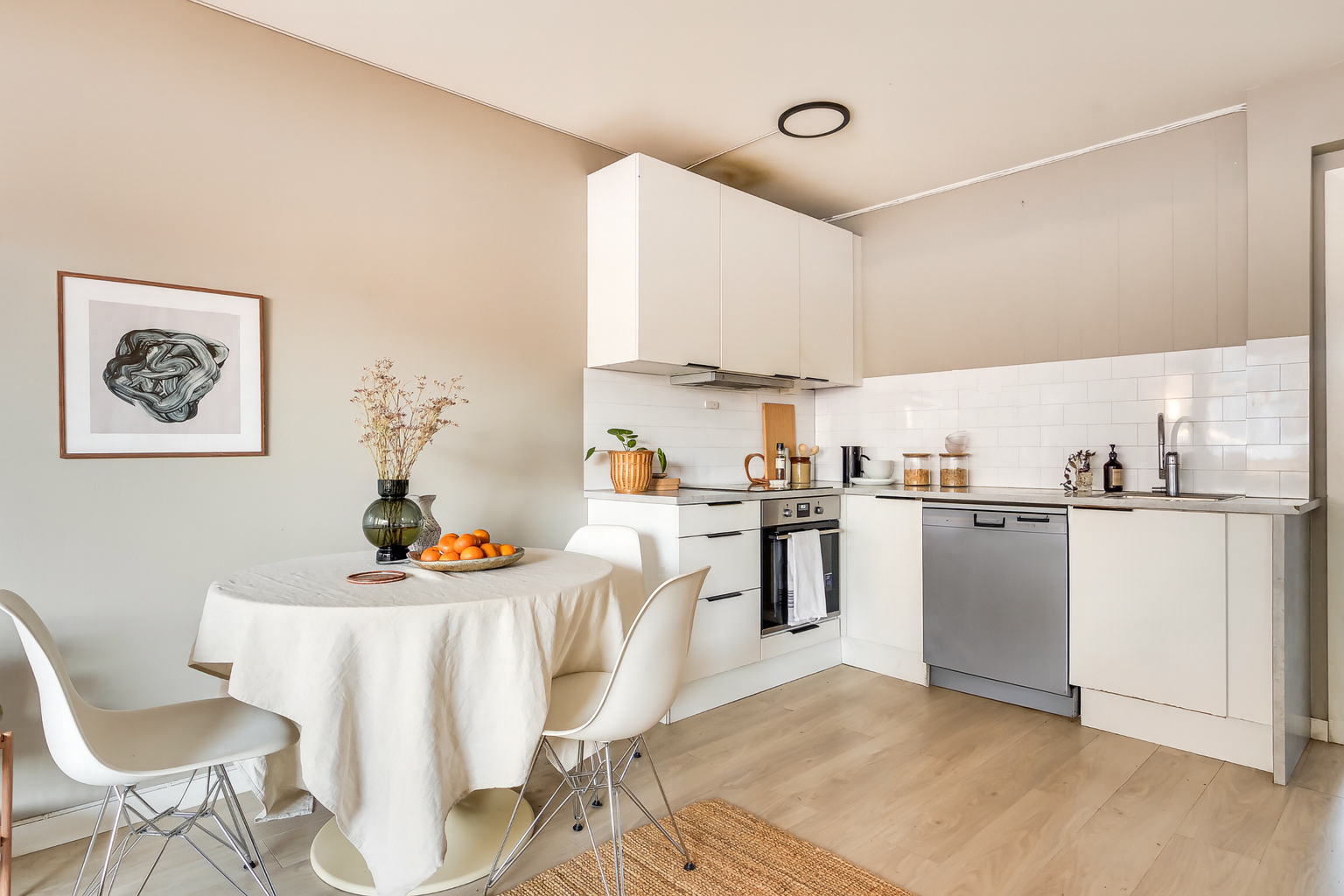 Kjøkkenet er tidløst med lyse, glatte overflater og benkeplate av laminat med stålkum. Galleribilde