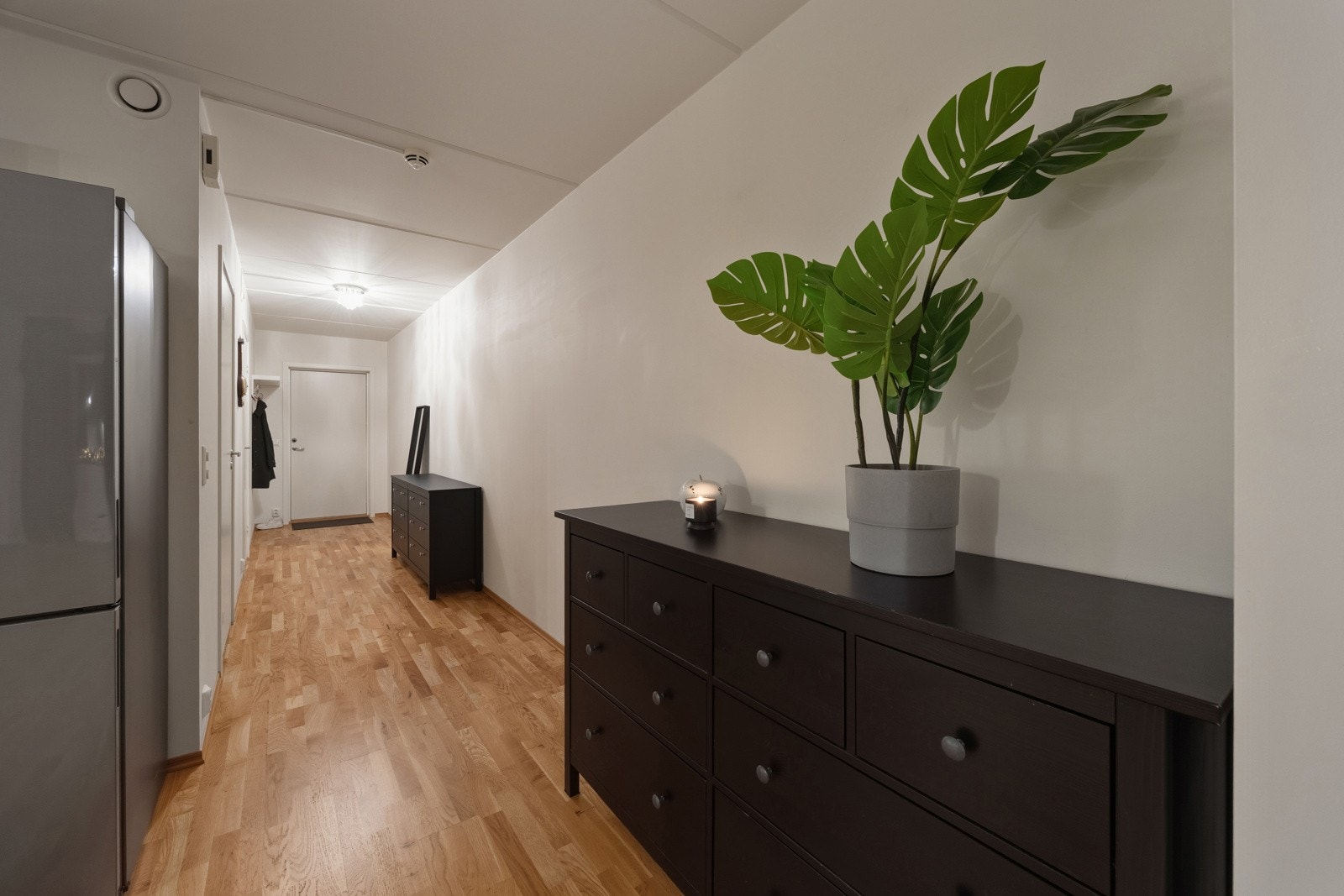 Innbydende entre/gang med lysmalte slette overflater og parkett på gulv, som gir et godt førsteinntrykk av leiligheten. Galleribilde