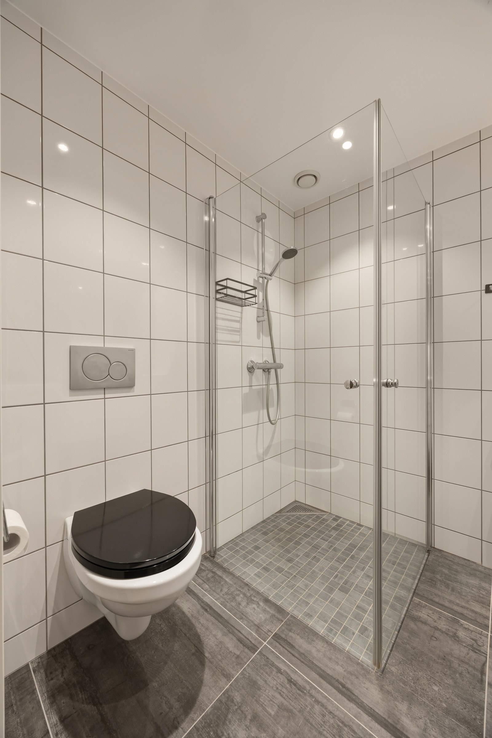 Videre har badet et separat dusjhjørne med innfellbare glassdører og hånddusj. Rommet har opplegg og plass for både vaskemaskin og tørketrommel i vaskesøyle. Himlingen er pent lyssatt med downlights. Galleribilde