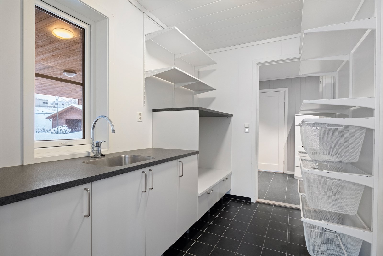 Romslig vaskerom med praktiske oppbevaringsløsninger og flislagt gulv med elektrisk gulvvarme. Galleribilde