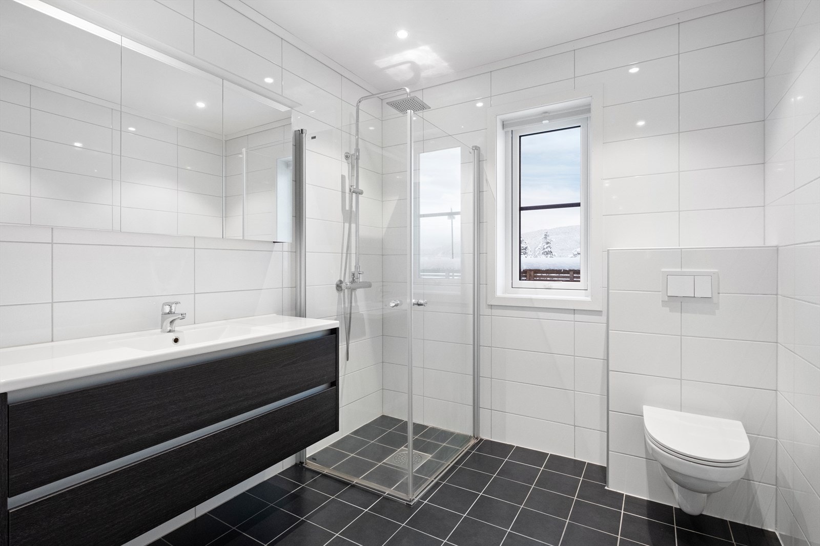 Badet er utstyrt med innredning med nedfelt servant, veggmontert toalett og dusjvegger/hjørne. Galleribilde