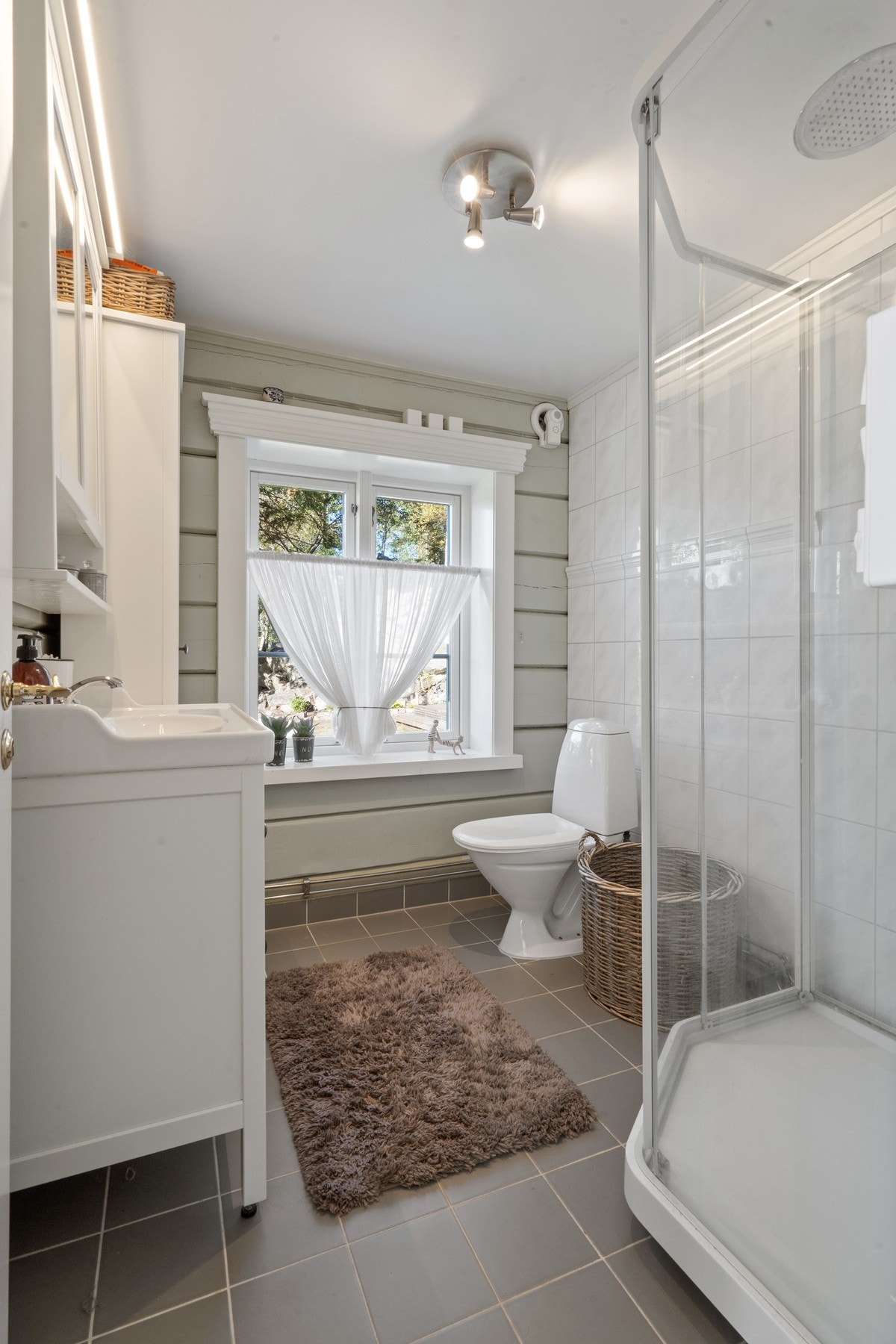 Badet er innredet med romslig servantskap med tilhørende veggskap, dusjkabinett og toalett. Galleribilde