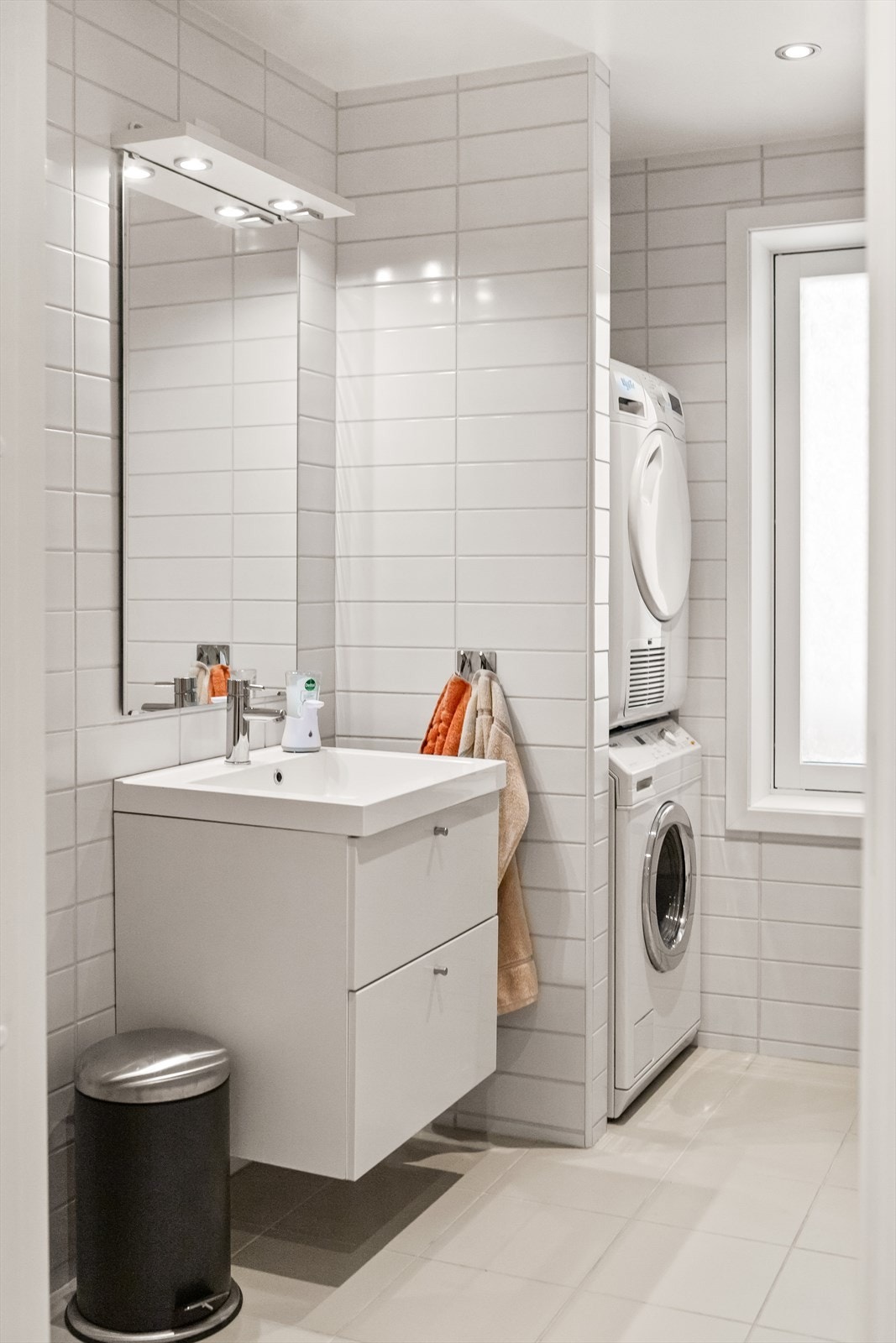 Badet er utstyrt med servantskap, samt overhengende speil med lys. Videre er det vegghengt toalett og dusjsone med inn- og utfeltbare dusjvegger. Det er opplegg for vaskemaskin og tørketrommel. Galleribilde