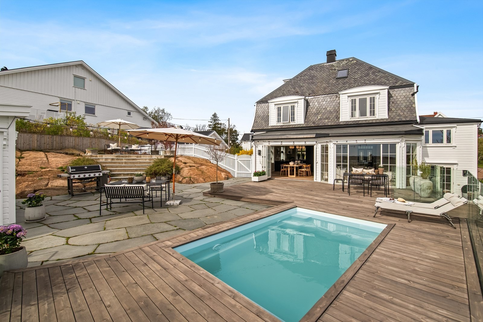 Uteområde er flott opparbeidet med terrasseplatting i tre og er delvis stenbelagt mot utestuen og bassenget. Galleribilde