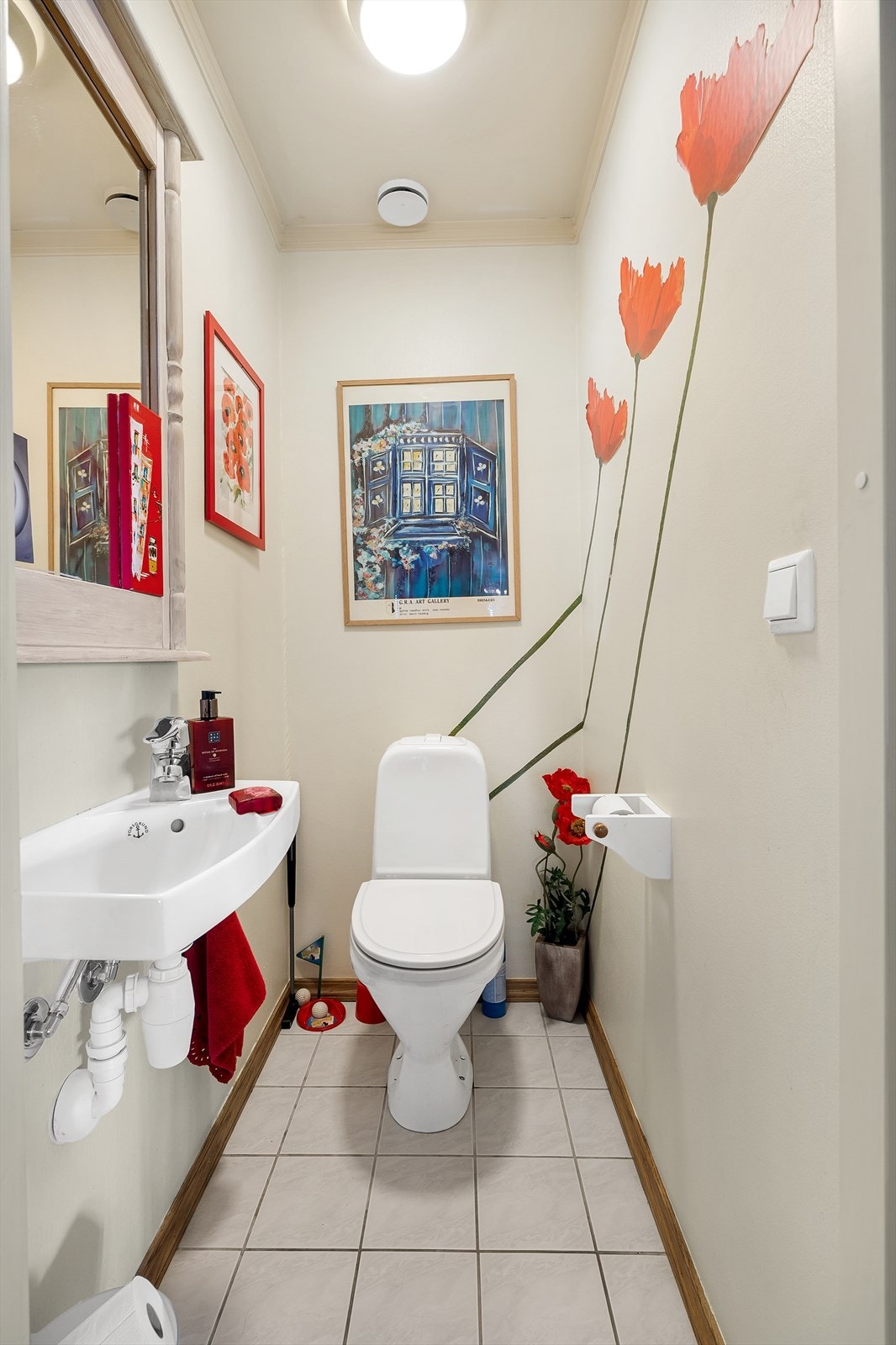 Separat toalettrom med flislagt gulv og malt tapet på veggene og malte himlingsflater. Rommet er utstyrt med vegghengt servantinnredning Galleribilde