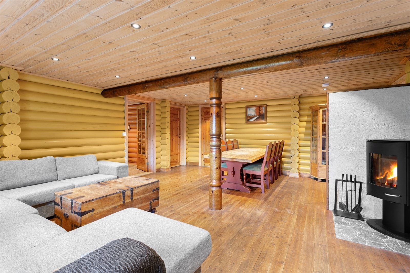 Innbydende stue med tregulv og laftet trepanel på vegg. Galleribilde