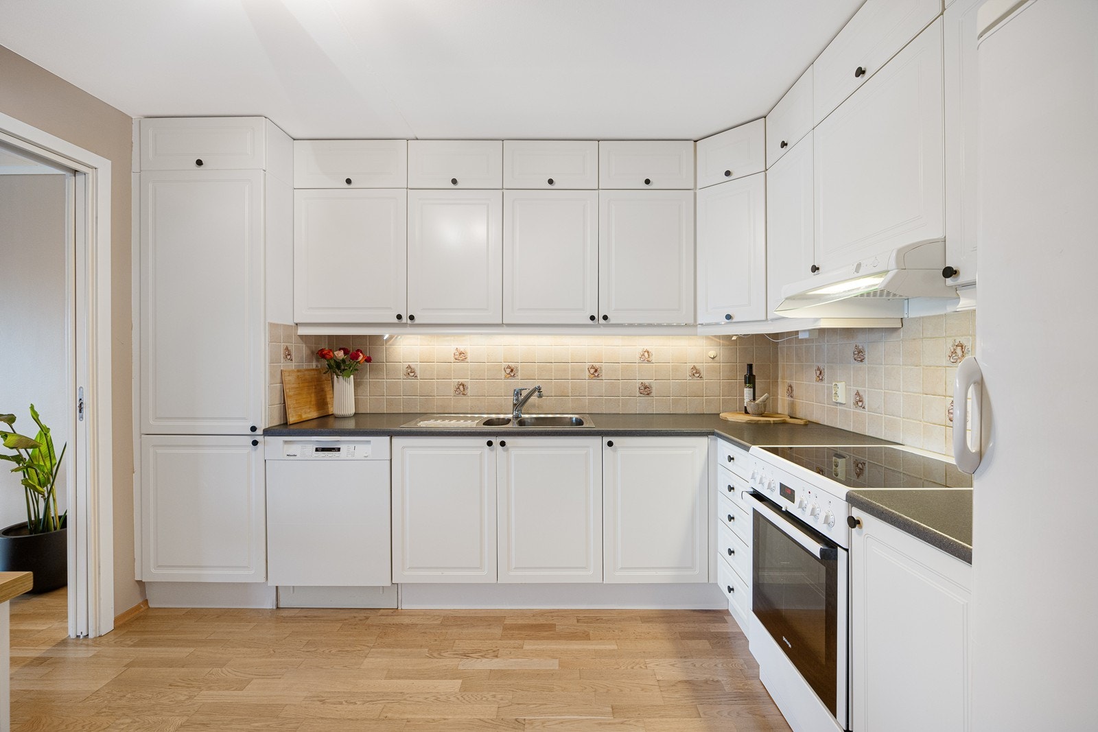 Innredningen er takhøy, oppført i en funksjonell L-form med god arbeidsflyt og skapplass Galleribilde