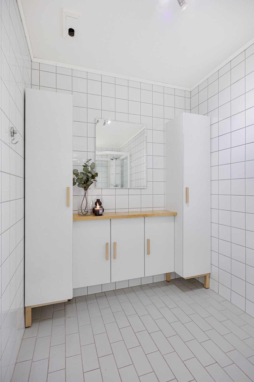 Langs den ene veggen er det satt inn et hvitt benkeskap med matchende høyskap på hver side Galleribilde