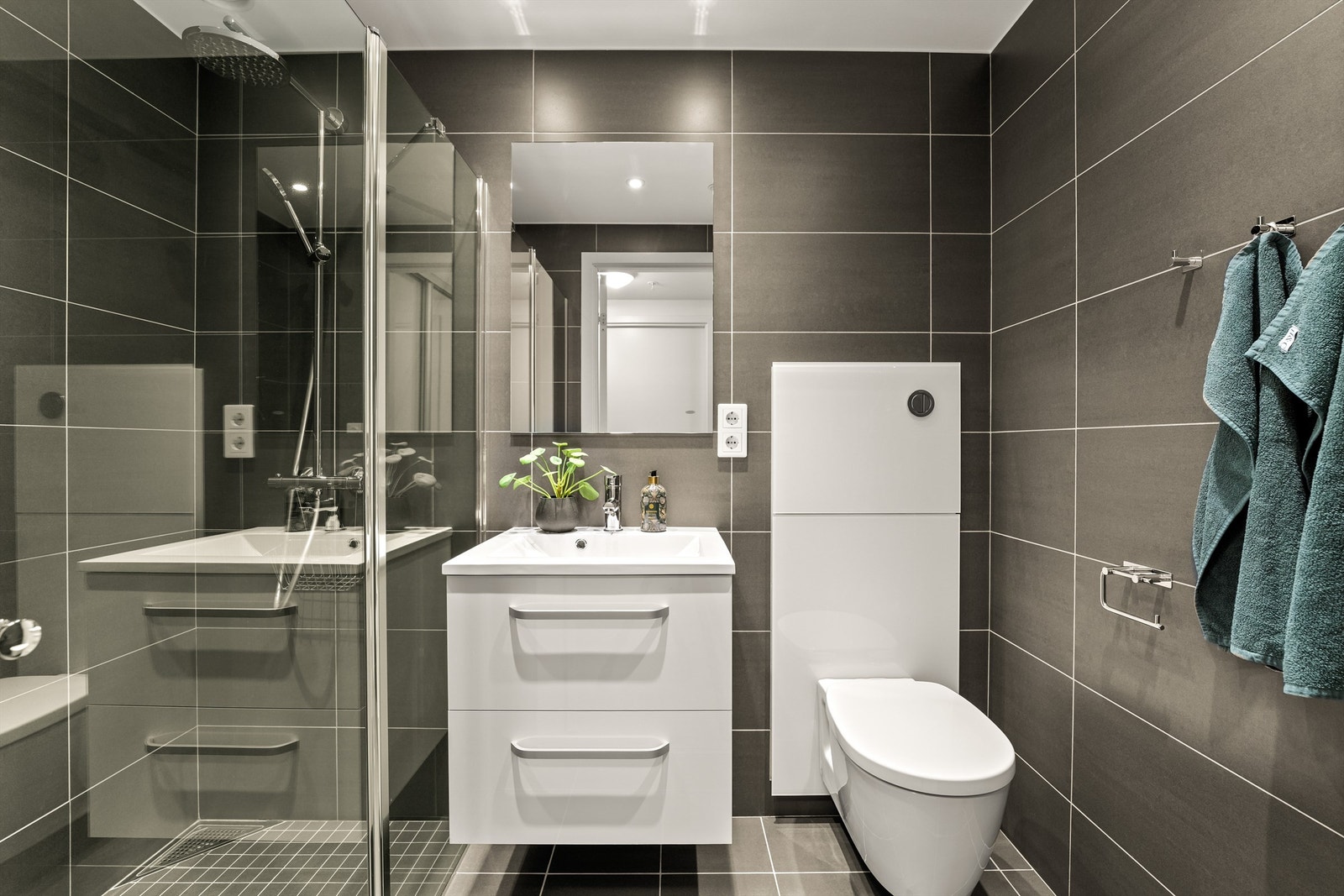 Begge badene har downlights, vegghengt toalett og et dusjhjørne med regnfallsdusj. Galleribilde