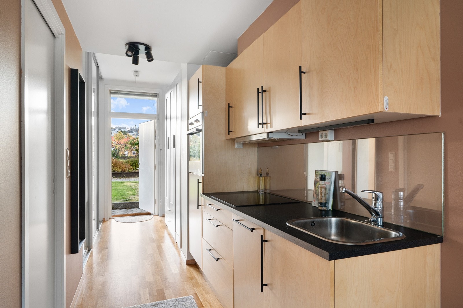 Når du åpner inngangsdøren til leiligheten, ønskes du velkommen inn i et lyst og innbydende rom, naturlig avdelt i entré, kjøkken og stuedel. Galleribilde