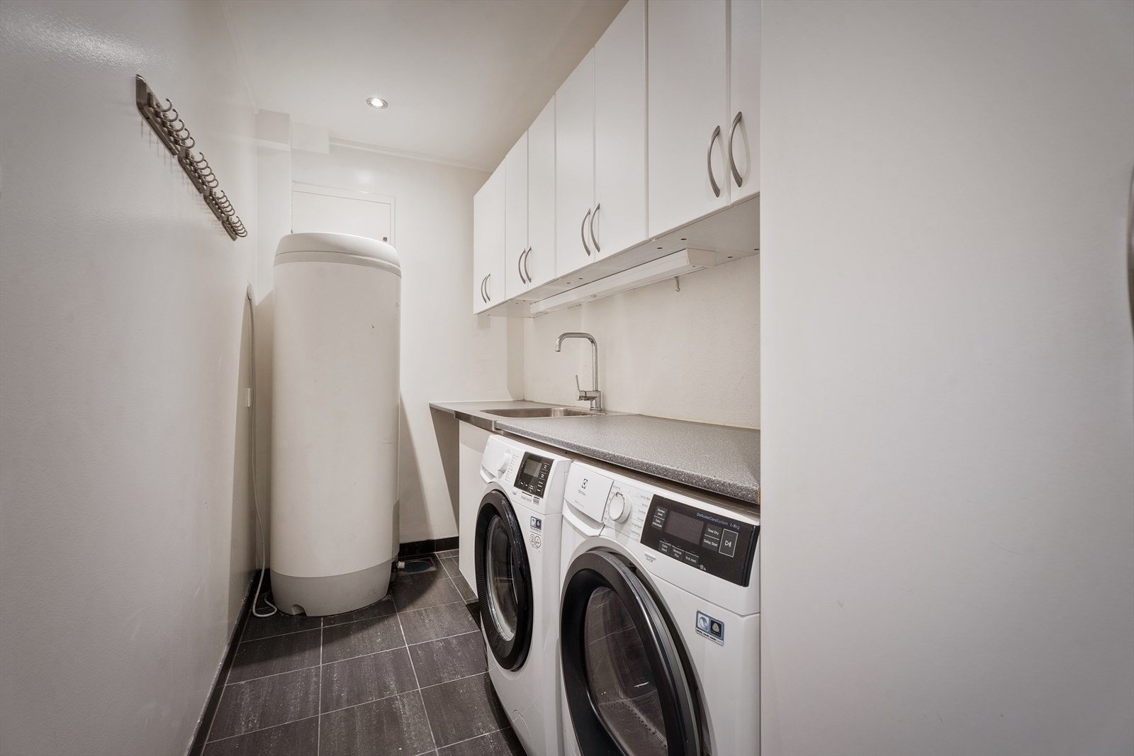 Lekkert og praktisk vaskerom med opplegg for både vaskemaskin og tørketrommel. Innredning med servant 1-greps blandebatteri og benkeplate av laminat. Galleribilde