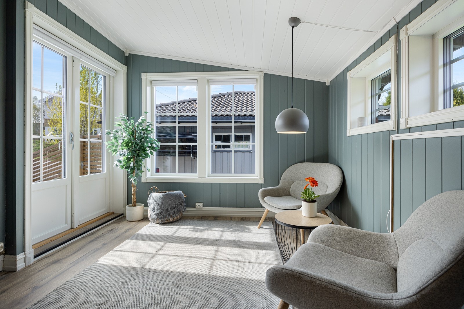 Det er flere vinduer i rommet, og det er også tofløyet dør ut mot terrassen og hagen Galleribilde