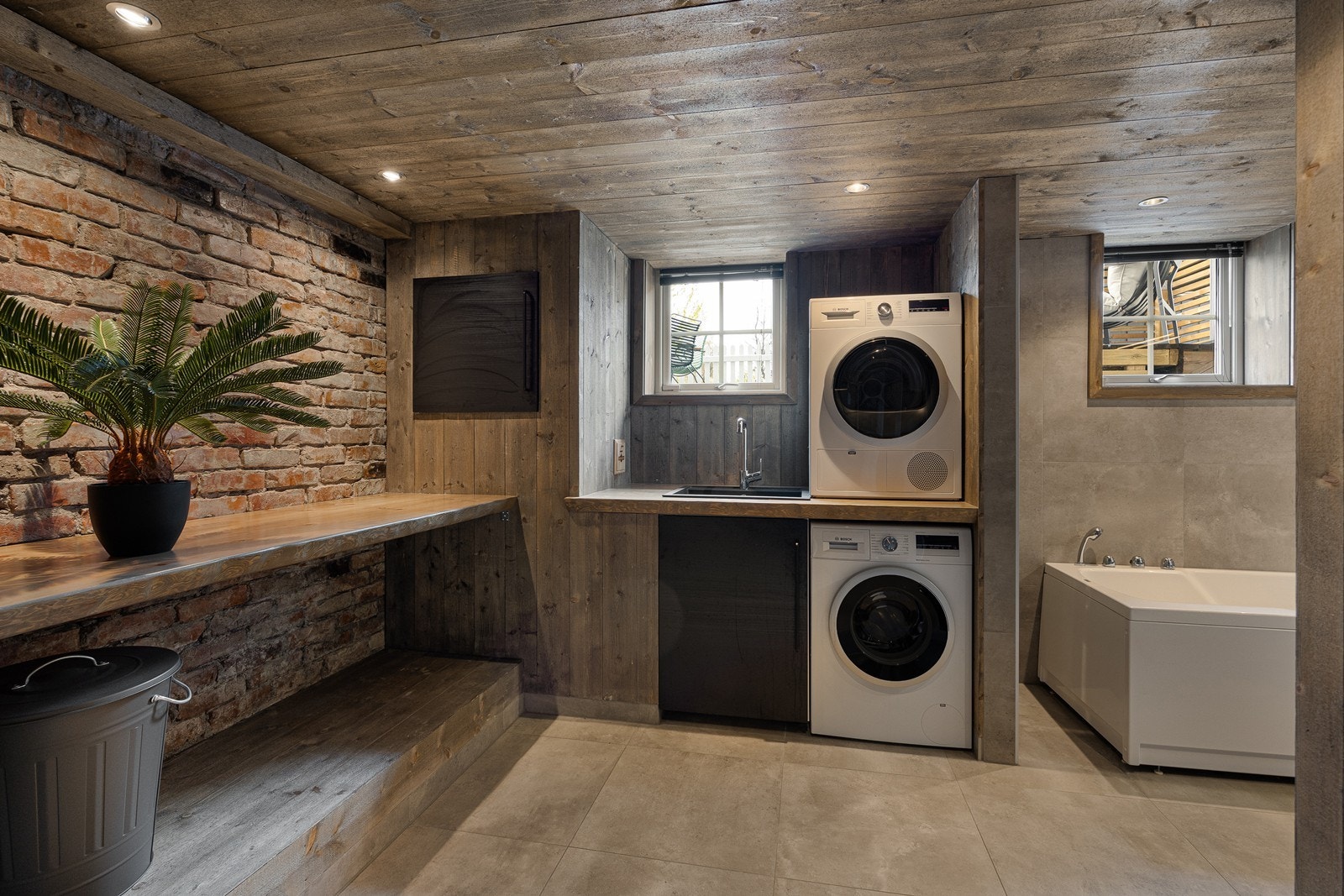 Badet i kjelleretasjen er kombinert bad/vaskerom og ble pusset opp i 2017. Rommet har en smakfull kombinasjon av store fliser på gulvet, fliser på deler av veggene og mørkbehandlet panel Galleribilde