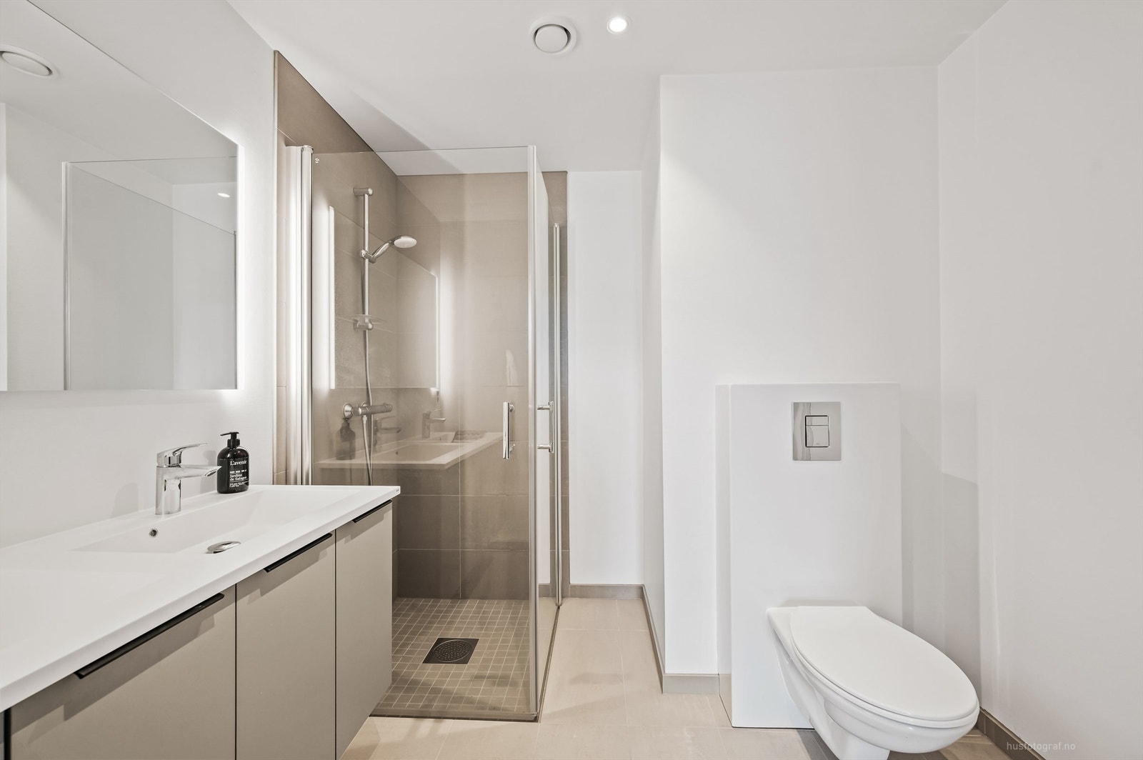 Badet har heldekkende dobbelservant og dusjhjørne med foldedører av glass Galleribilde