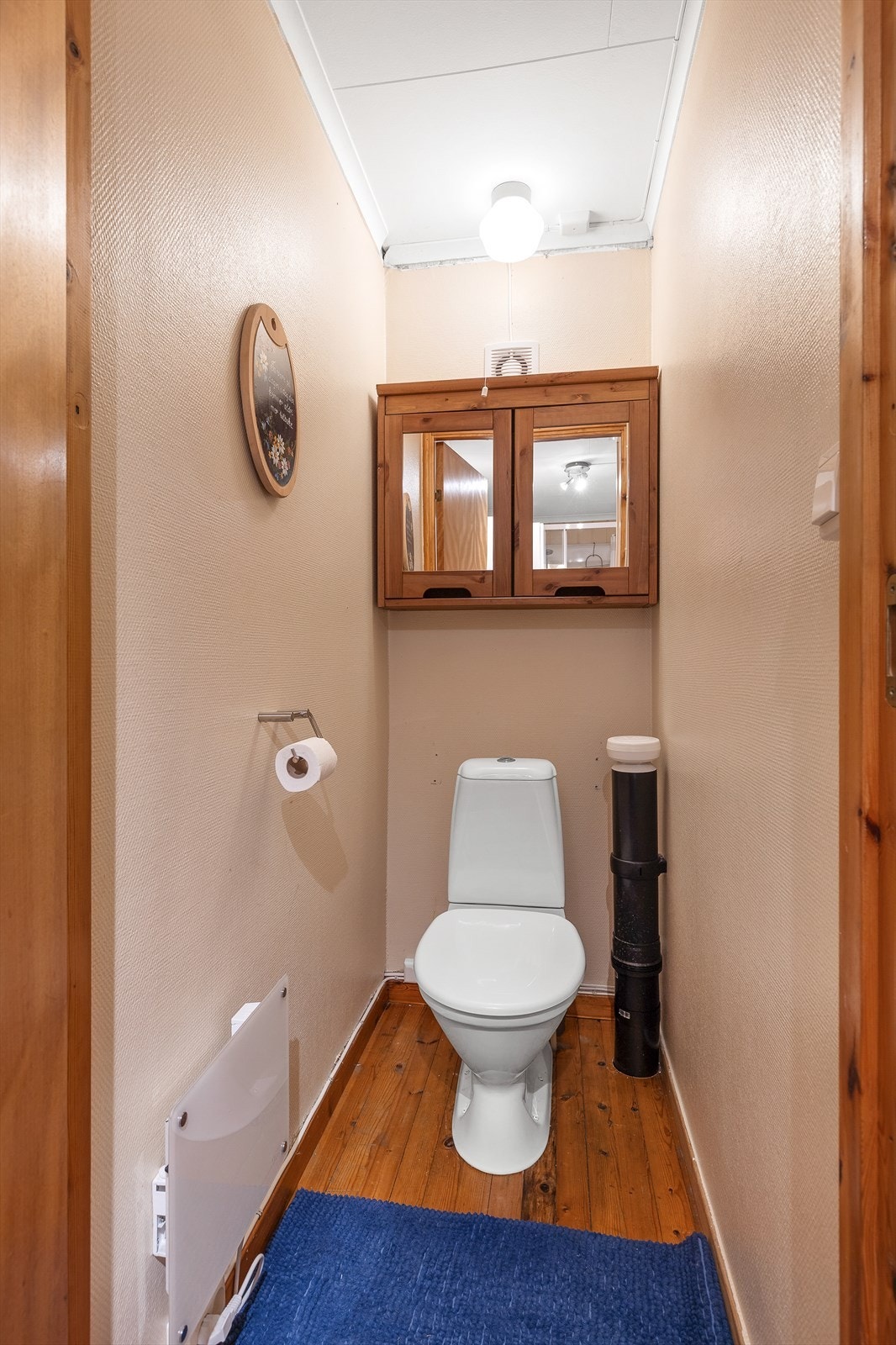 Wc-rom med gulvbord av heltre, tapet på vegger og folierte plater i himling Galleribilde