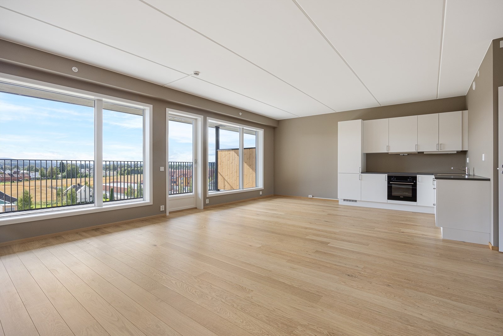 Rommet har store, sørvendte vinduer og utgang til en solfylt balkong Galleribilde