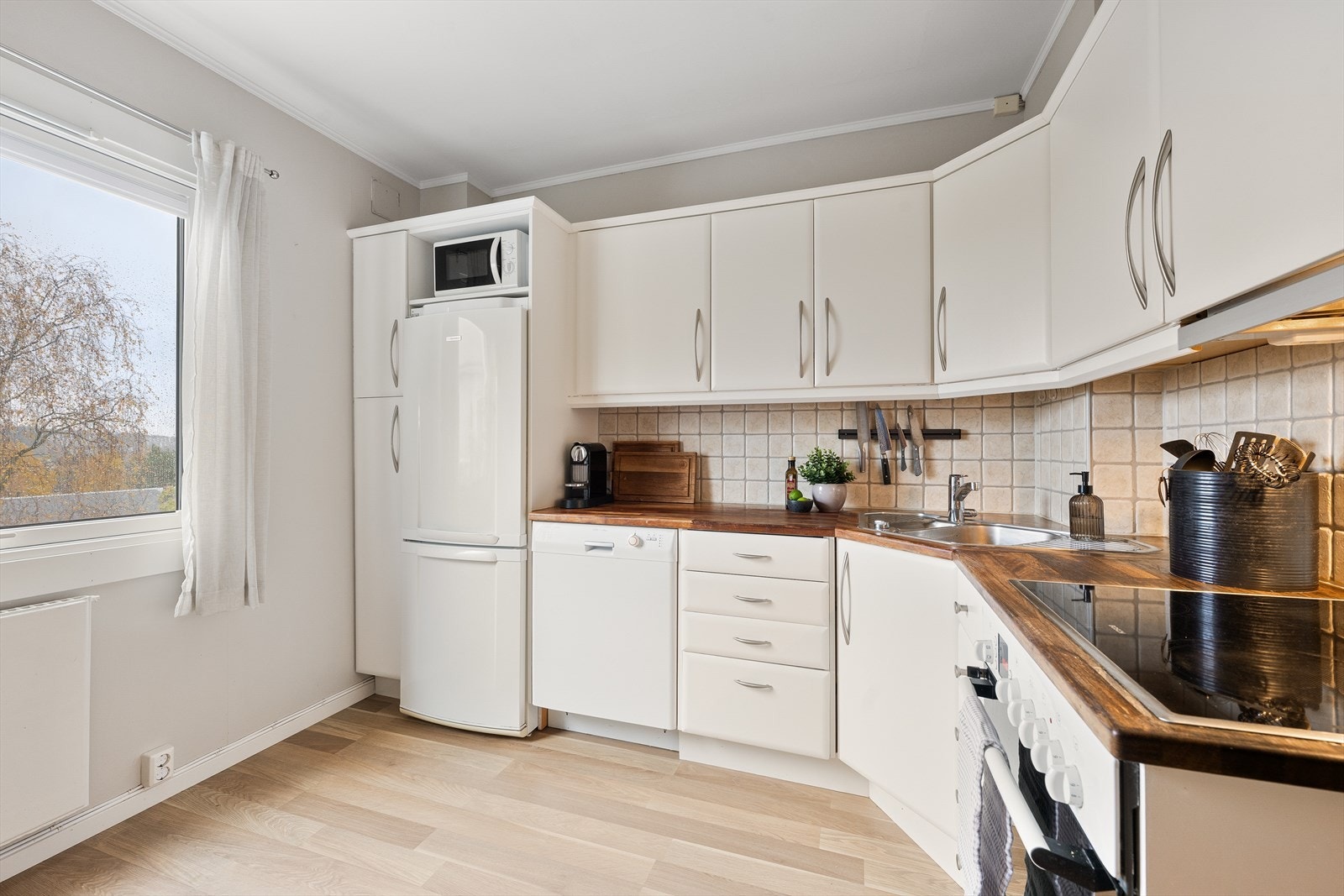 Kjøkkenet har nedfelt stålvask og integrerte hvitevarer, inkludert platetopp og stekeovn Galleribilde