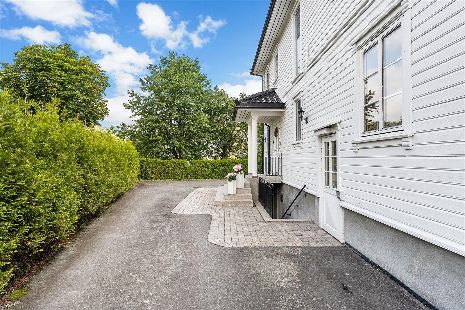 Asfaltert innkjørsel leder til husets hovedinngang. Galleribilde