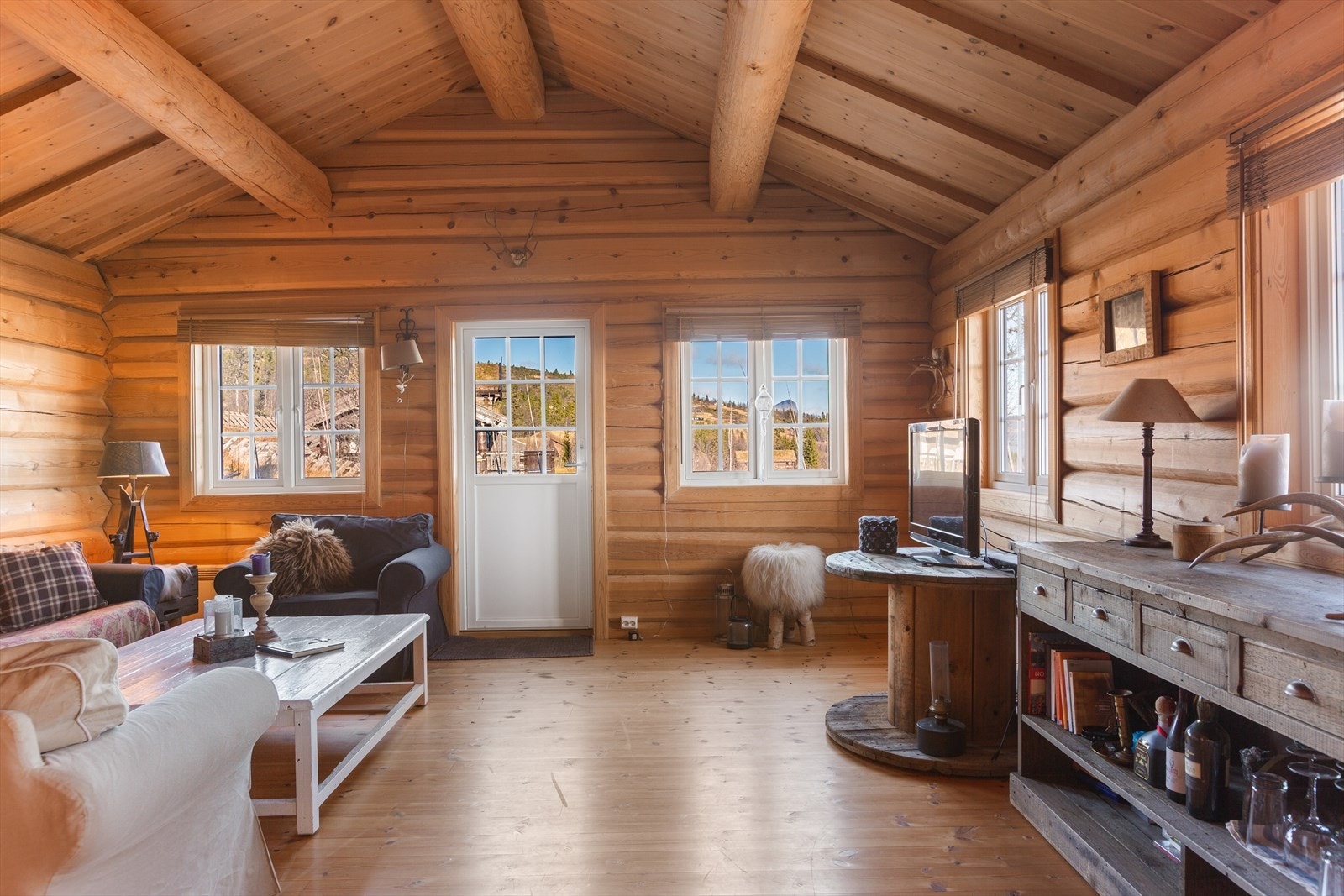 I stuen får du umiddelbart den gode hyttefølelsen med tømmervegger og rausta himling med tømmeråser. Galleribilde