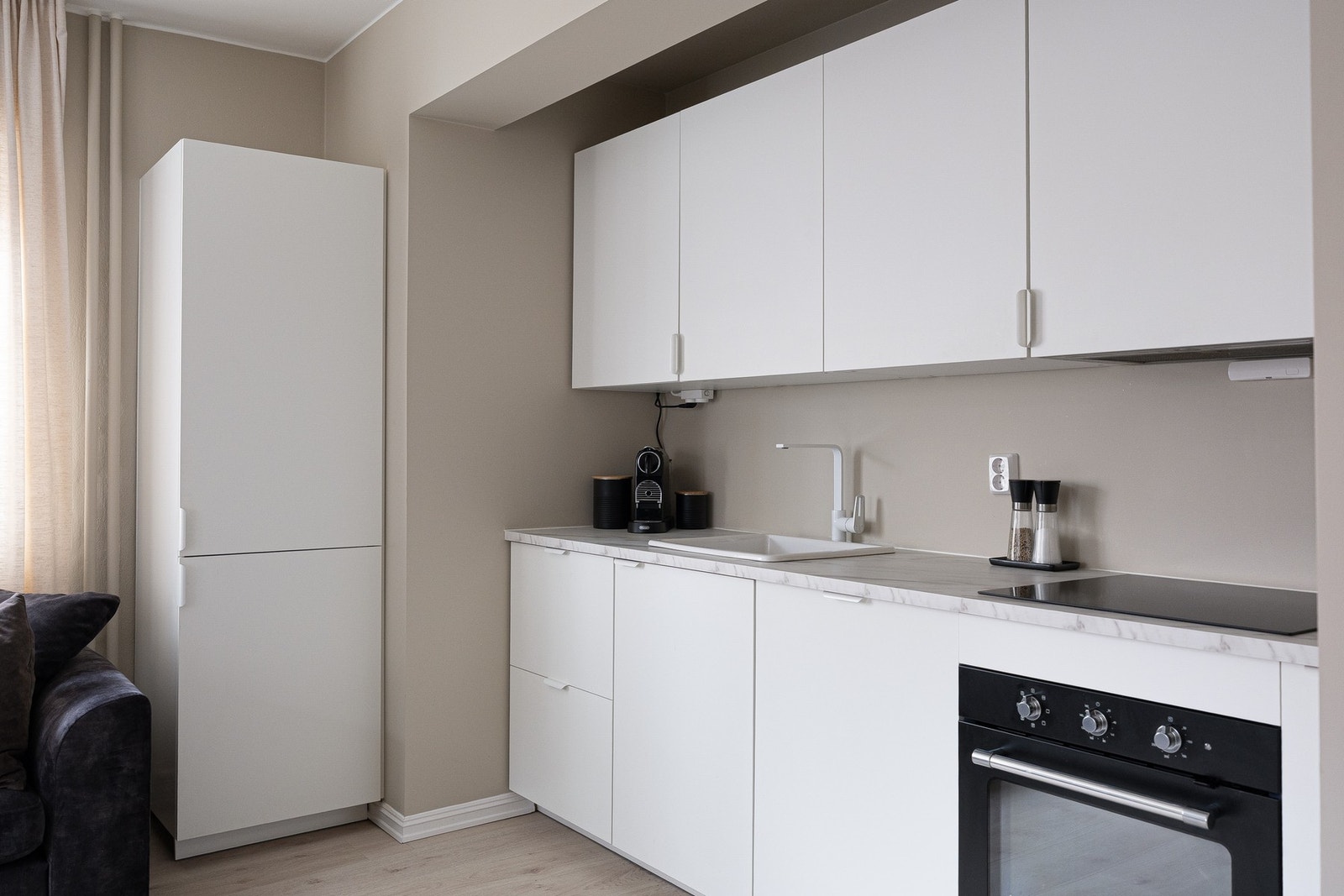 Lys og stilren kjøkkeninnredning fra 2023. Kjøkkenet har et sømløst uttrykk med integrert oppvaskmaskin, kjøl/fryseskap, stekeovn og induksjon platetopp. Galleribilde