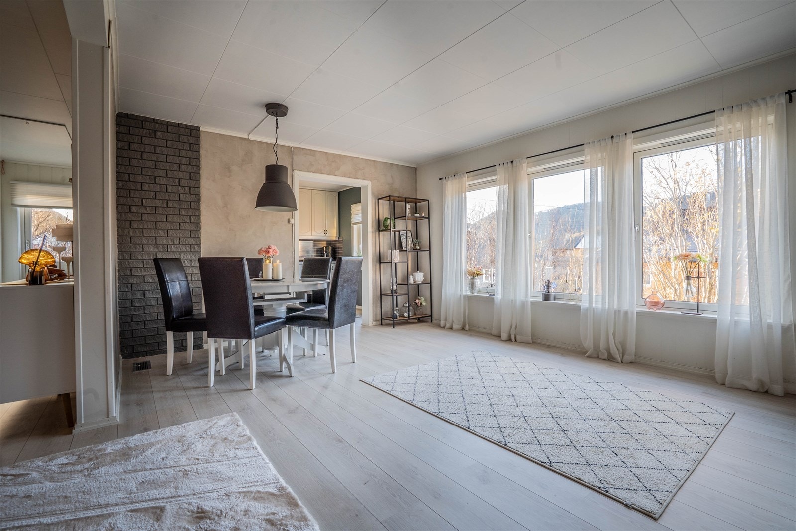 Lys og romslig stue med store vinduer som gir godt med naturlig lys og utsikt mot naturomgivelser. Galleribilde