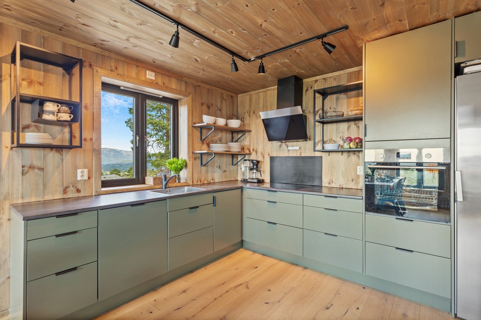 På kjøkkenet er det fin, moderne grønn kjøkkeninnredning med glatte fronter, laminert benkeplate og integrerte hvitevarer. Kjøleskapet er ikke integrert. Galleribilde