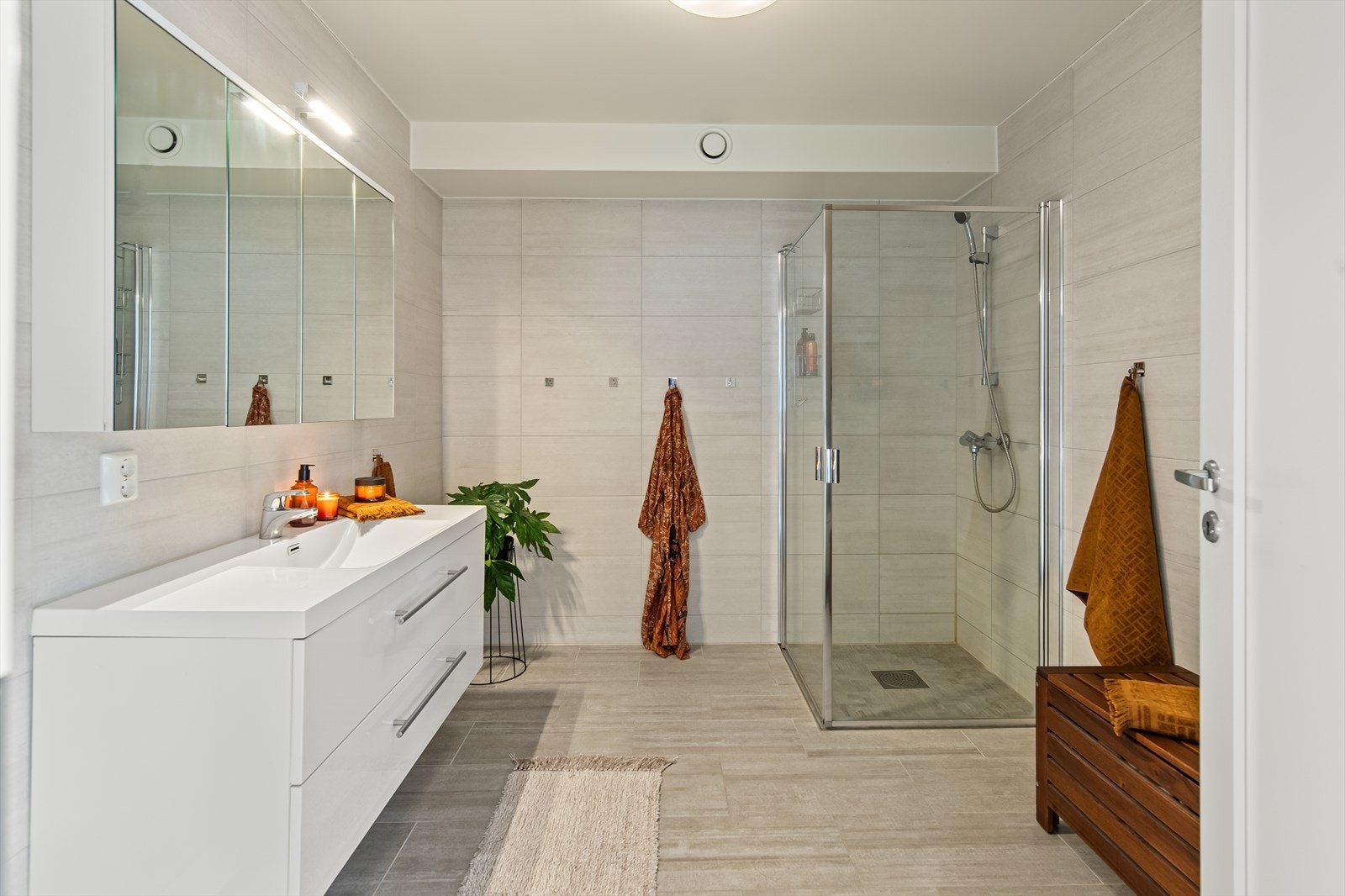 Baderommet inneholder vegghengt toalett, innredning med servant, speilskap og dusj med dusj/vegger. Galleribilde