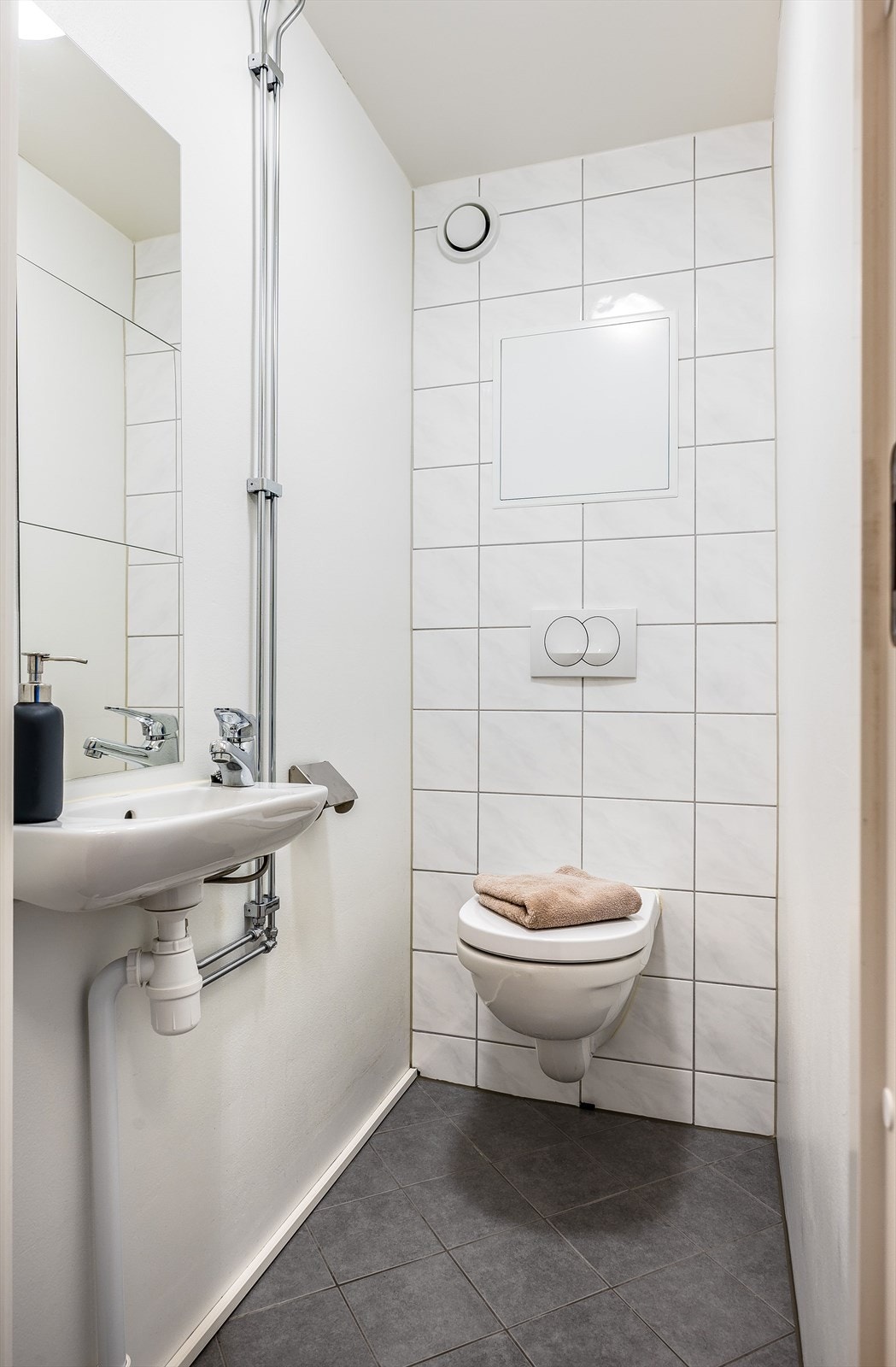 Vegg-i-vegg med baderommet har du et lyst og praktisk separat toalettrom. Toalettrommet er utstyrt med vegghengt servant med speil over, vegghengt toalett og mekanisk avtrekk. Galleribilde