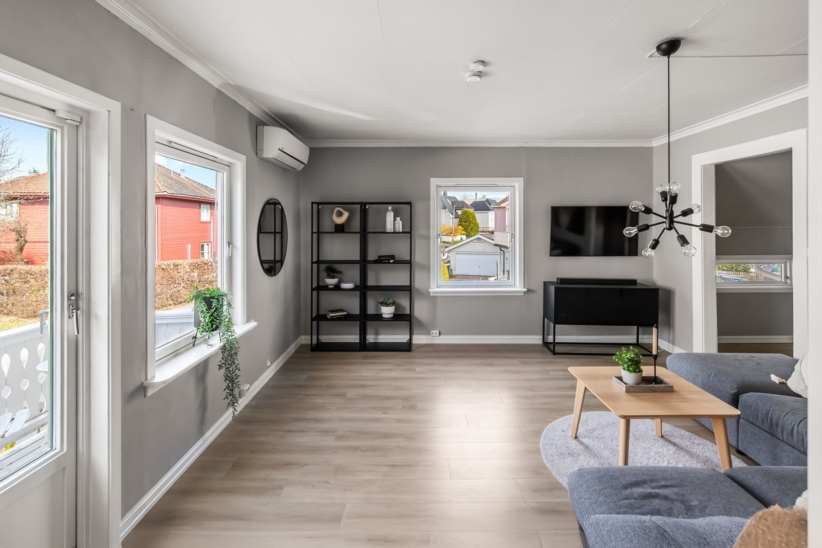 Veggene er malt i en dus gråtone som fremhever laminatgulvet, og i stuesonen er det montert en luft-til-luft varmepumpe. Galleribilde