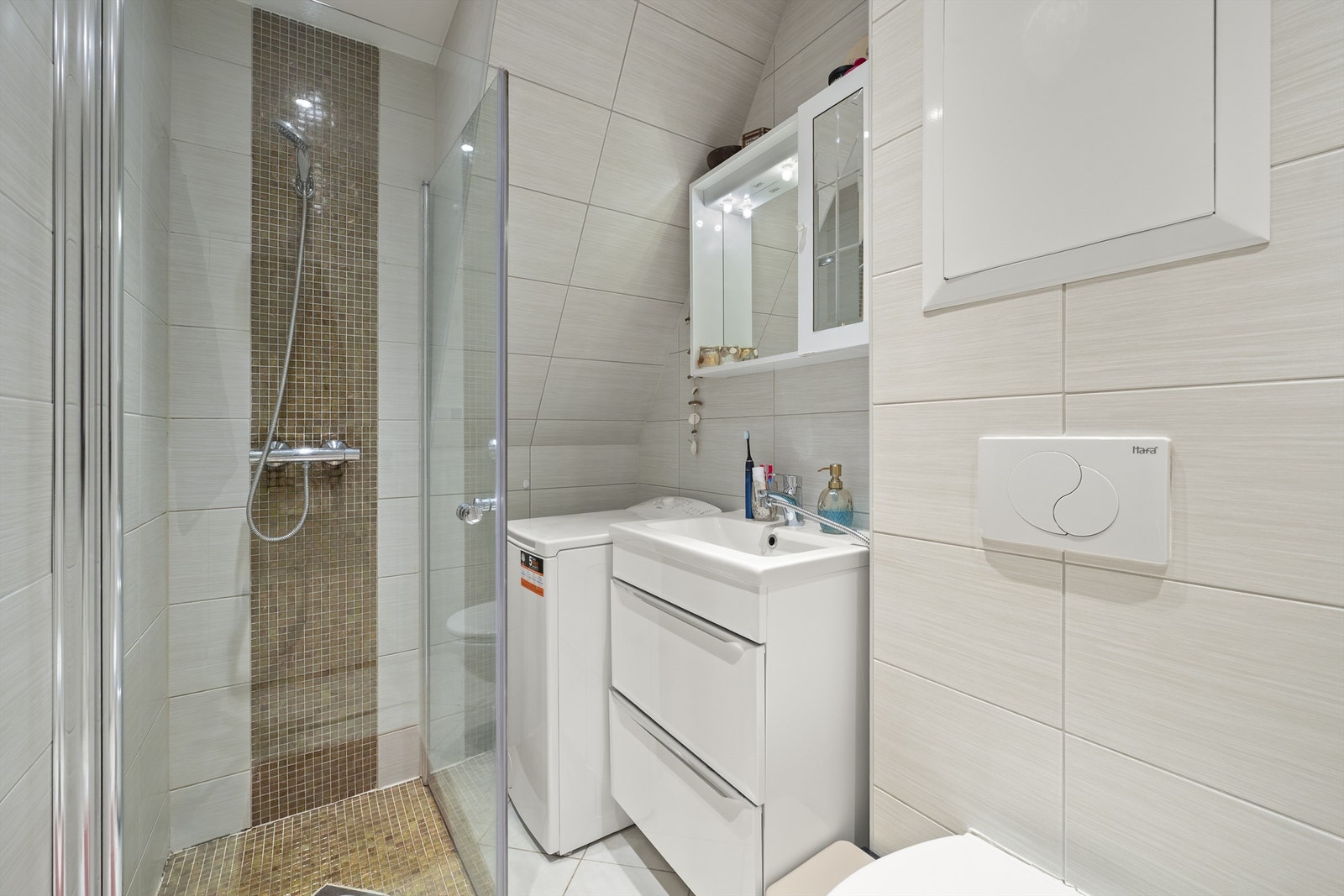 Stilrent og funksjonelt bad med flislagte gulv ned varme og vegger, samt himling med downlights. Rommet er utstyrt med moderne innredning, heldekkende servant, overskap med speil og vegghengt toalett Galleribilde