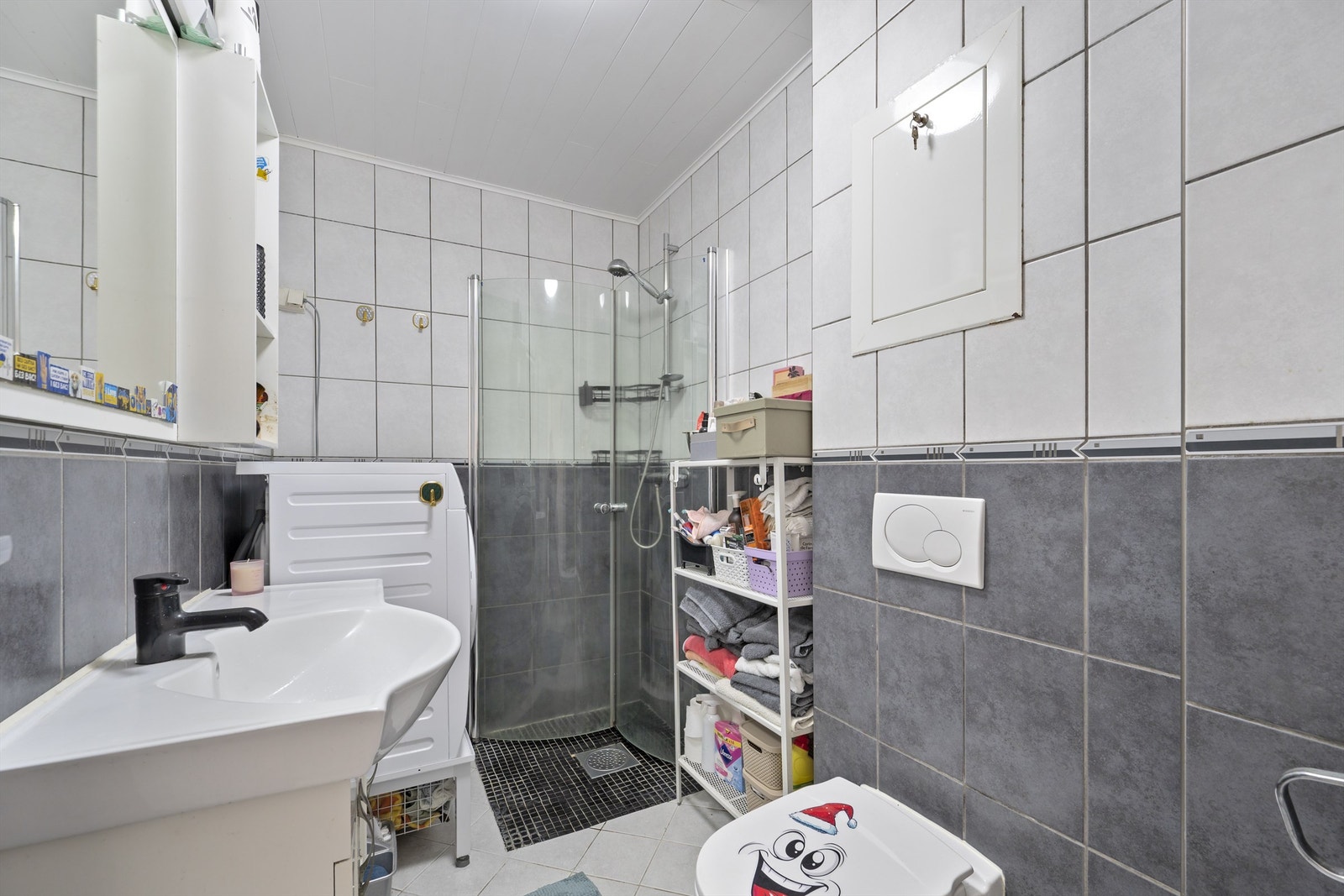 Pent flislagt bad med gulvarme. Innredningen består av heldekkende servant, overskap og speil. Vegghengt toalett, dusjhjørne med innfellbare glassdører. Opplegg for vaskemaskin - mekanisk avtrekk Galleribilde