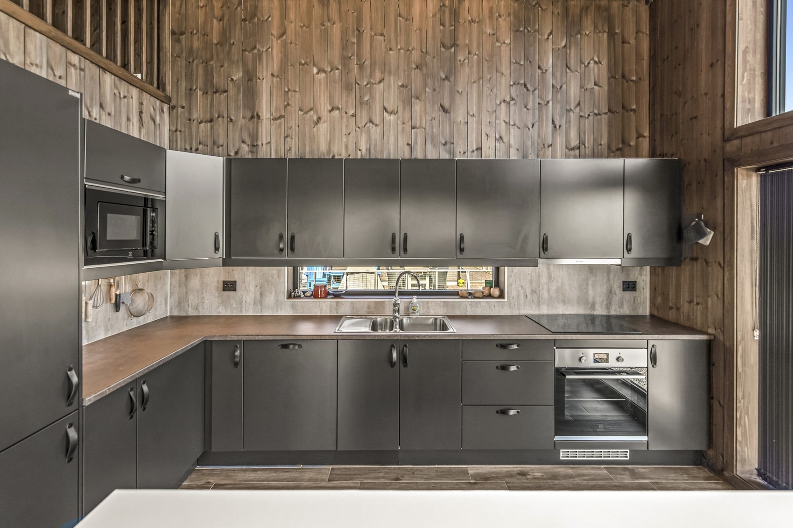 Den åpne kjøkken- og stueløsningen er hyttens hjerte, med vindusflater fra gulv til tak som gir panoramautsikt uansett hvor du oppholder deg i rommet. Galleribilde