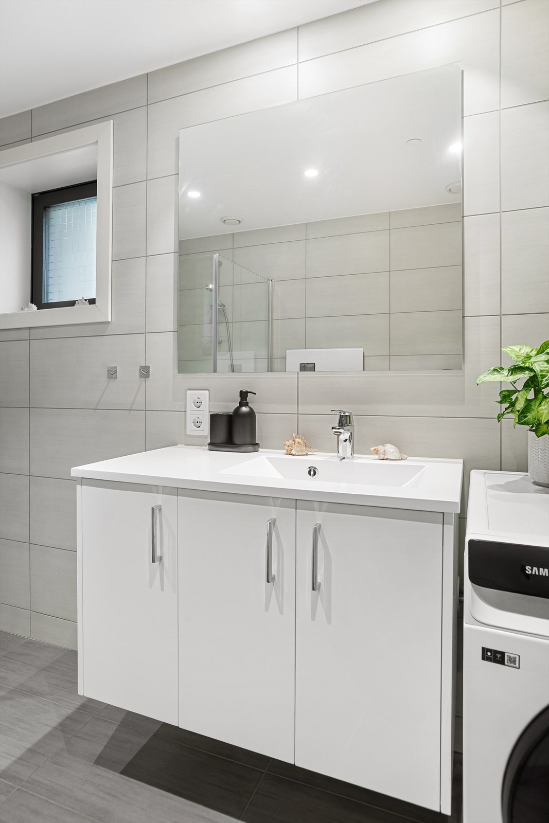 Badet er utstyrt med heldekkende servant med underskap, speil, dusjnisje og veggmontert toalett Galleribilde