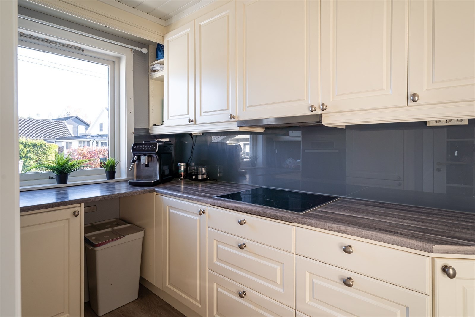 Innredningen er montert i hesteskoform og har hvite, profilerte fronter, vitrineskap og mørke laminatbenkeplater. I benken er det nedfelt oppvaskkum og koketopp, og veggene bak er beskyttet med glassplater. Galleribilde