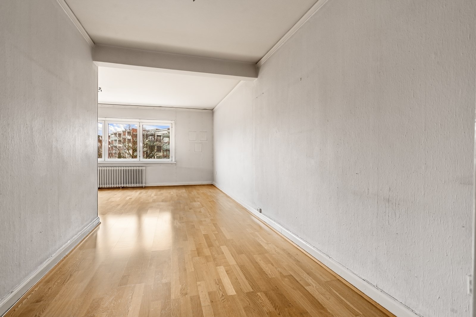 Stue sett fra soverom og hall. Om sommeren er det hyggelige grønne trær utenfor vinduet. Galleribilde