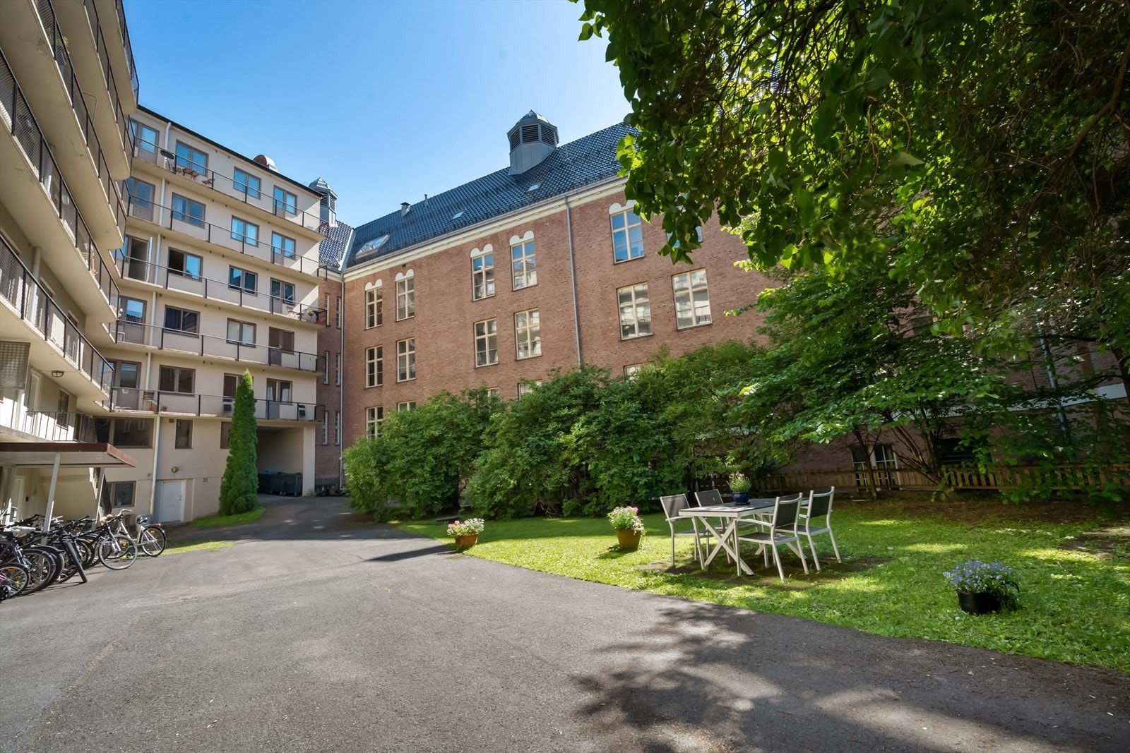 Sommerbilde. Felles bakgård med sykkelparkering og sittegruppe. Galleribilde