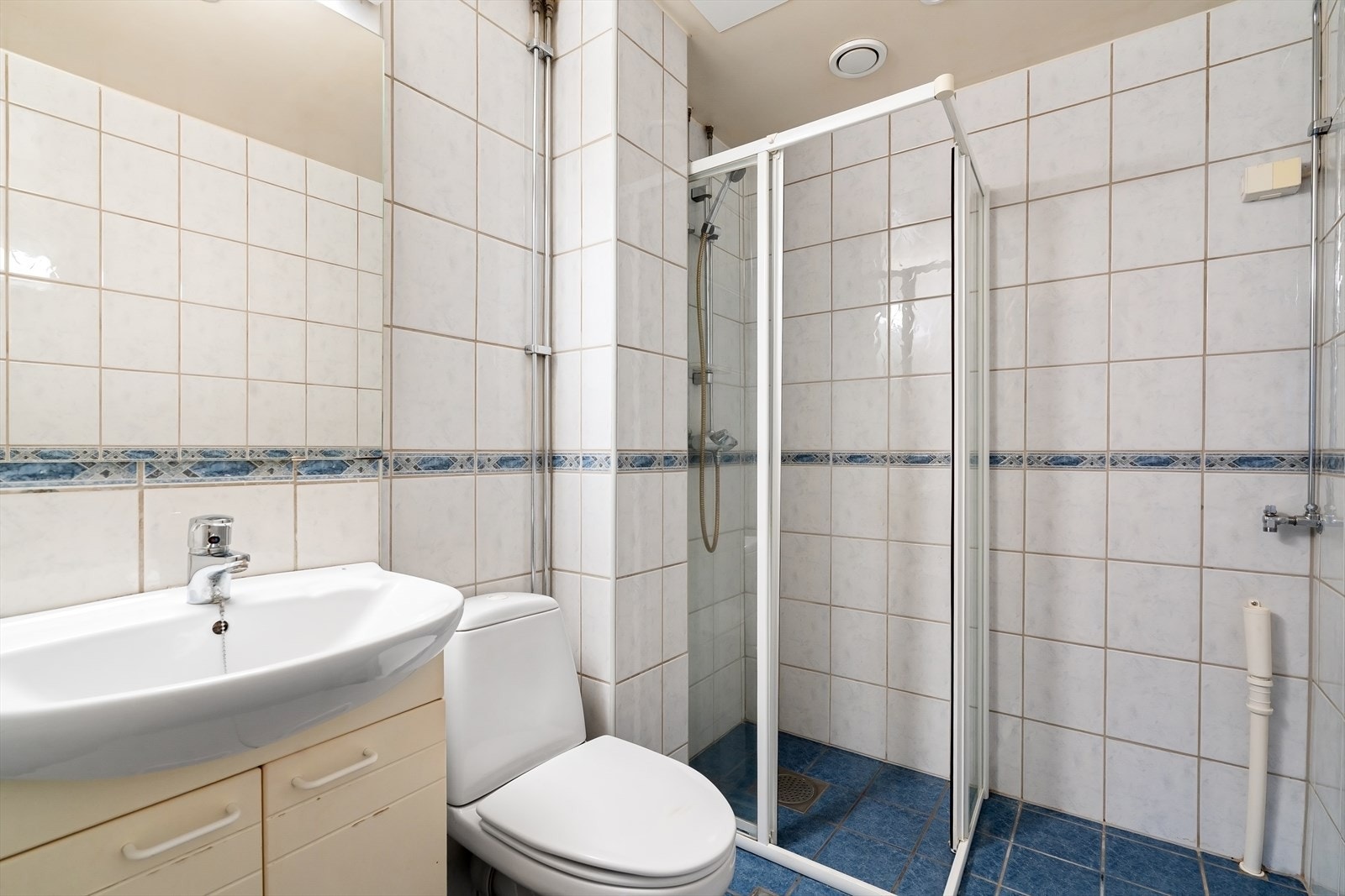 Eldre bad med dusj, toalett og servantinnredning. Galleribilde