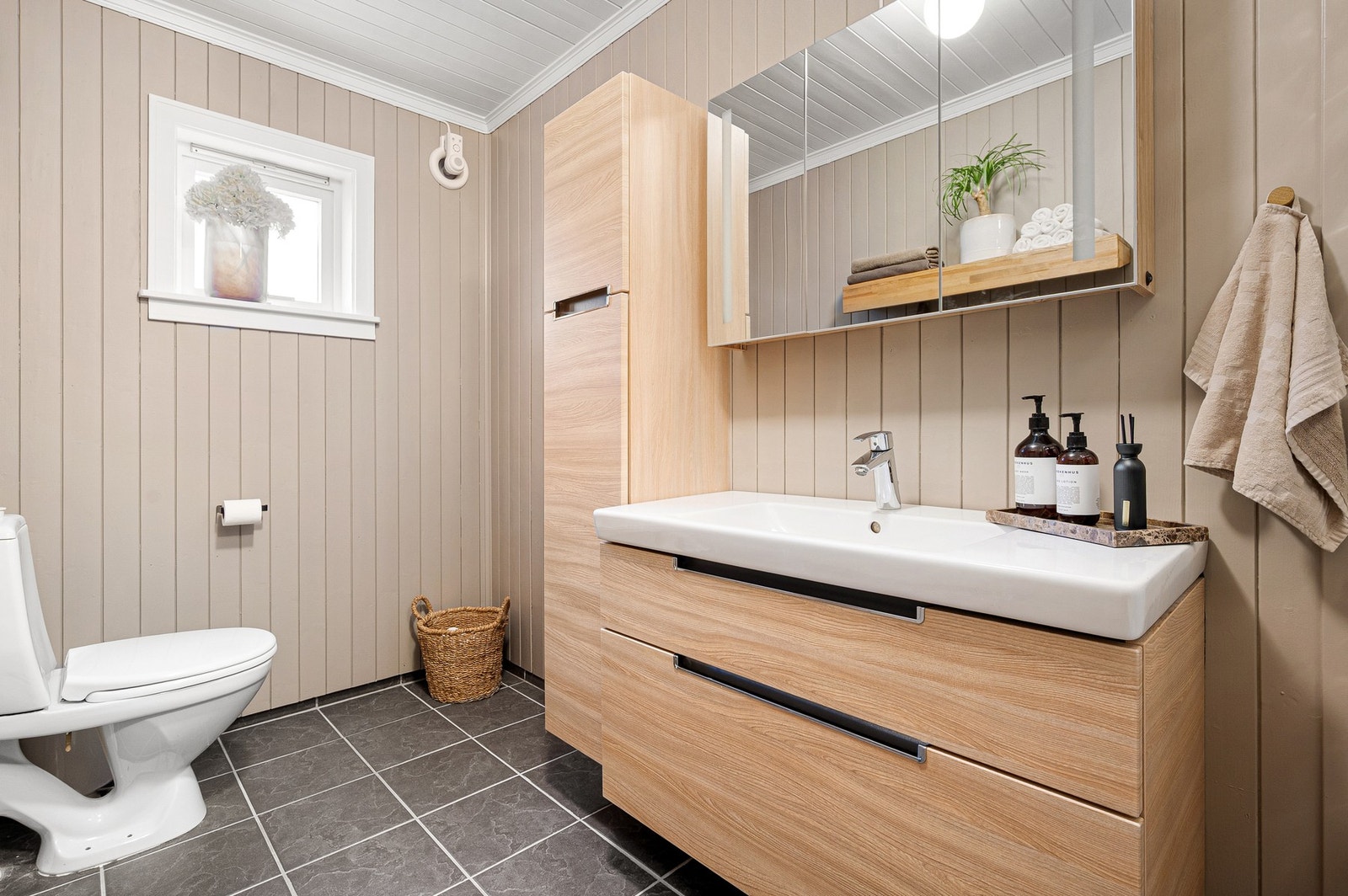 Boligens ene bad - praktisk plassert like ved inngangsdøren. Pent og romslig bad, med et nordisk uttrykk. Mye oppbevaringsplass i skuffer og skap - også oppbevaringsplass i speilskapet. Galleribilde