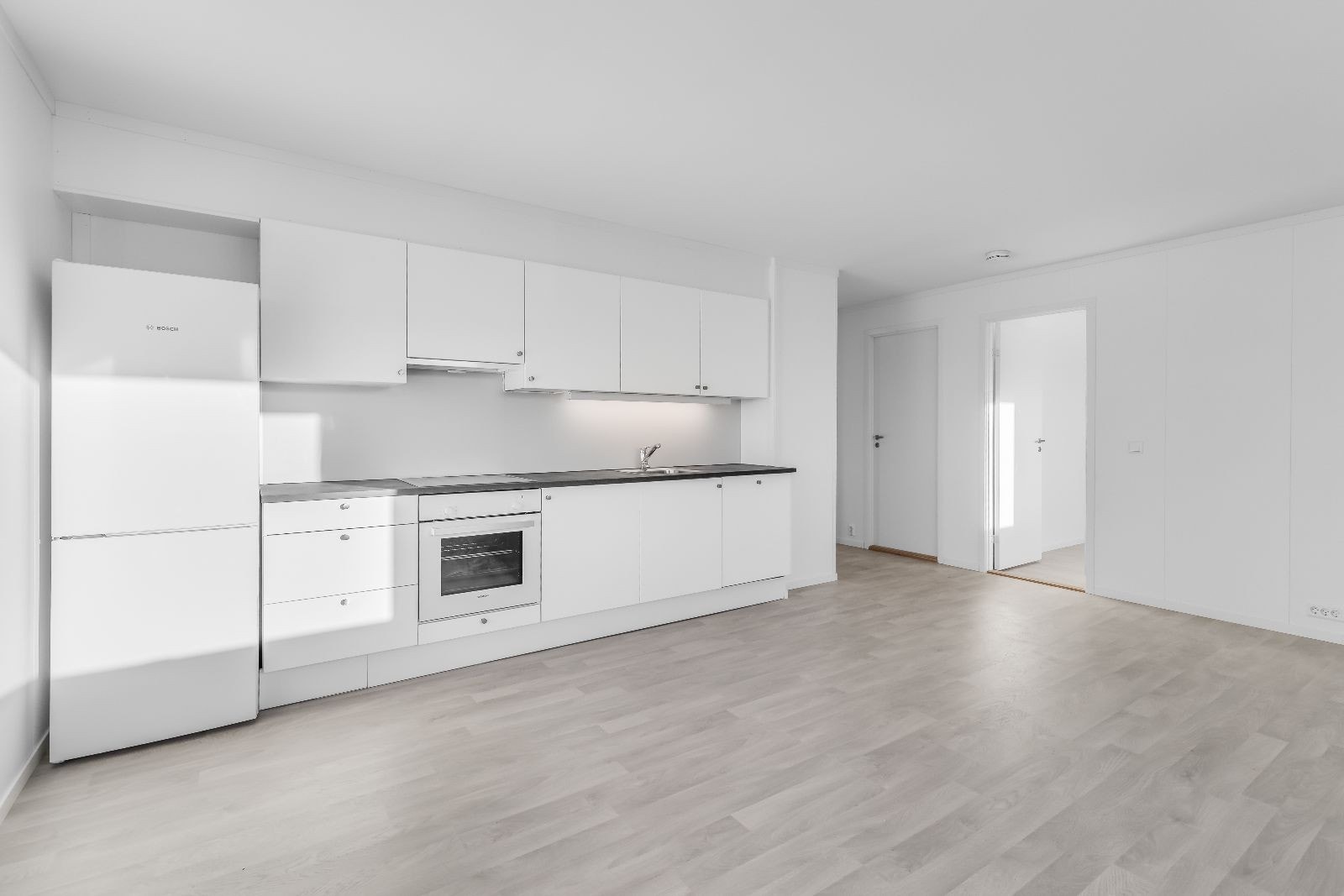 Åpen stue- og kjøkkenløsning med lysmalte flater Galleribilde