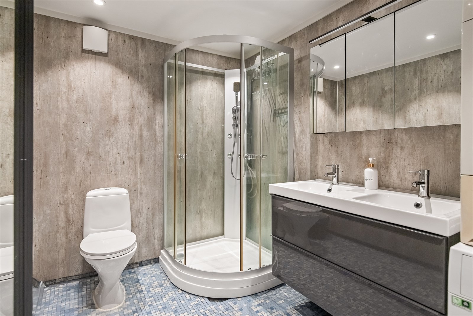 Badet i underetasjen er også overflateoppusset i 2022 med nye veggflater, ny baderomsinnredning, samt dusjkabinett. Det er overflater av fliser på gulv og baderomsplater på vegger og det er varmekabler i gulv. Galleribilde