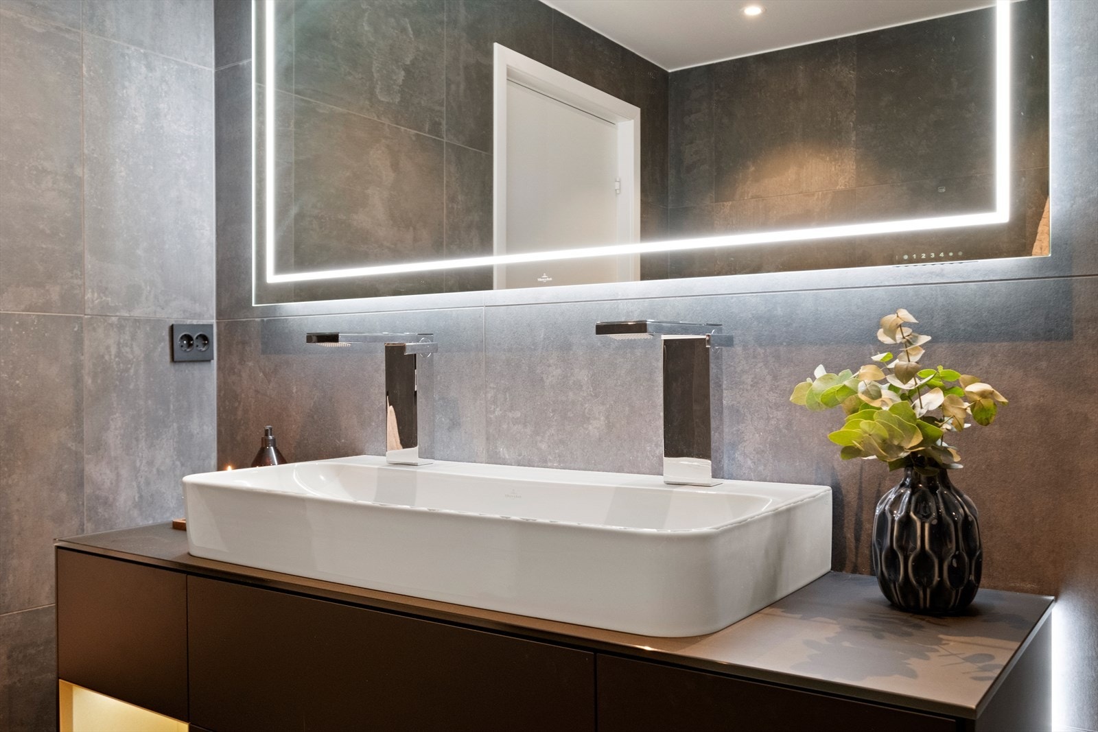 Innredning med servant og to blandebatterier. Speil på badet har Bluetooth høyttalere og fjernkontroll for justering av lys i speil Galleribilde