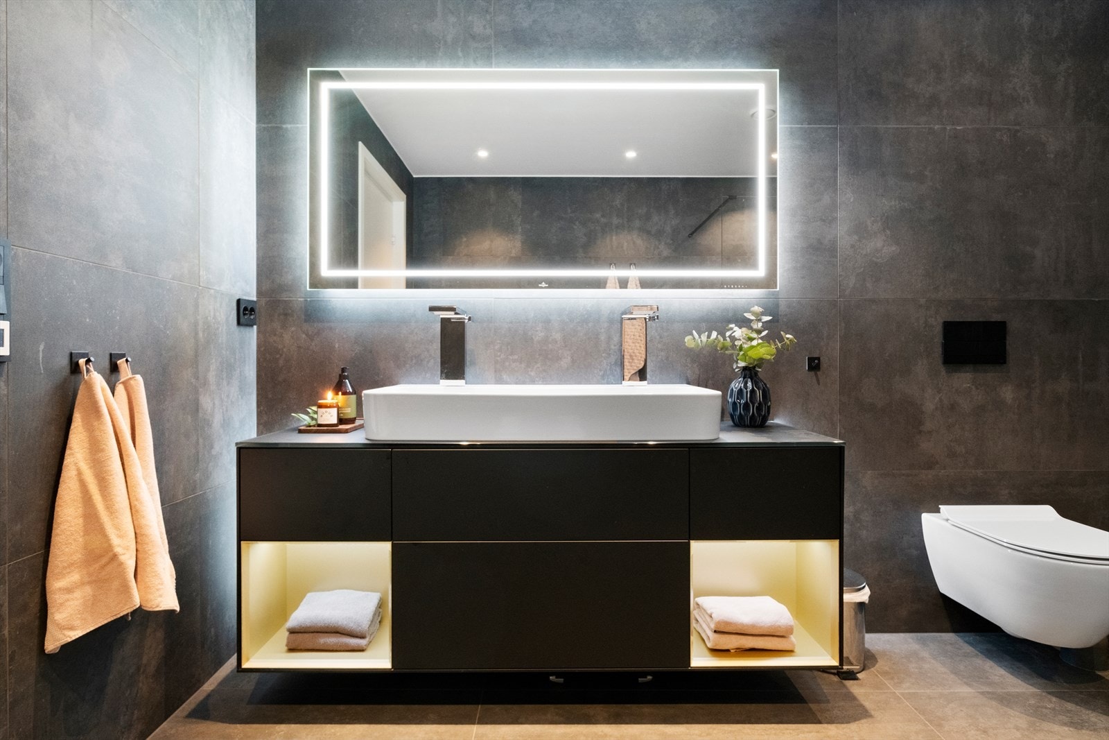 Badet er utstyrt med toalett, dusjvegg i glass og innredning med servant og to blandebatterier. Galleribilde