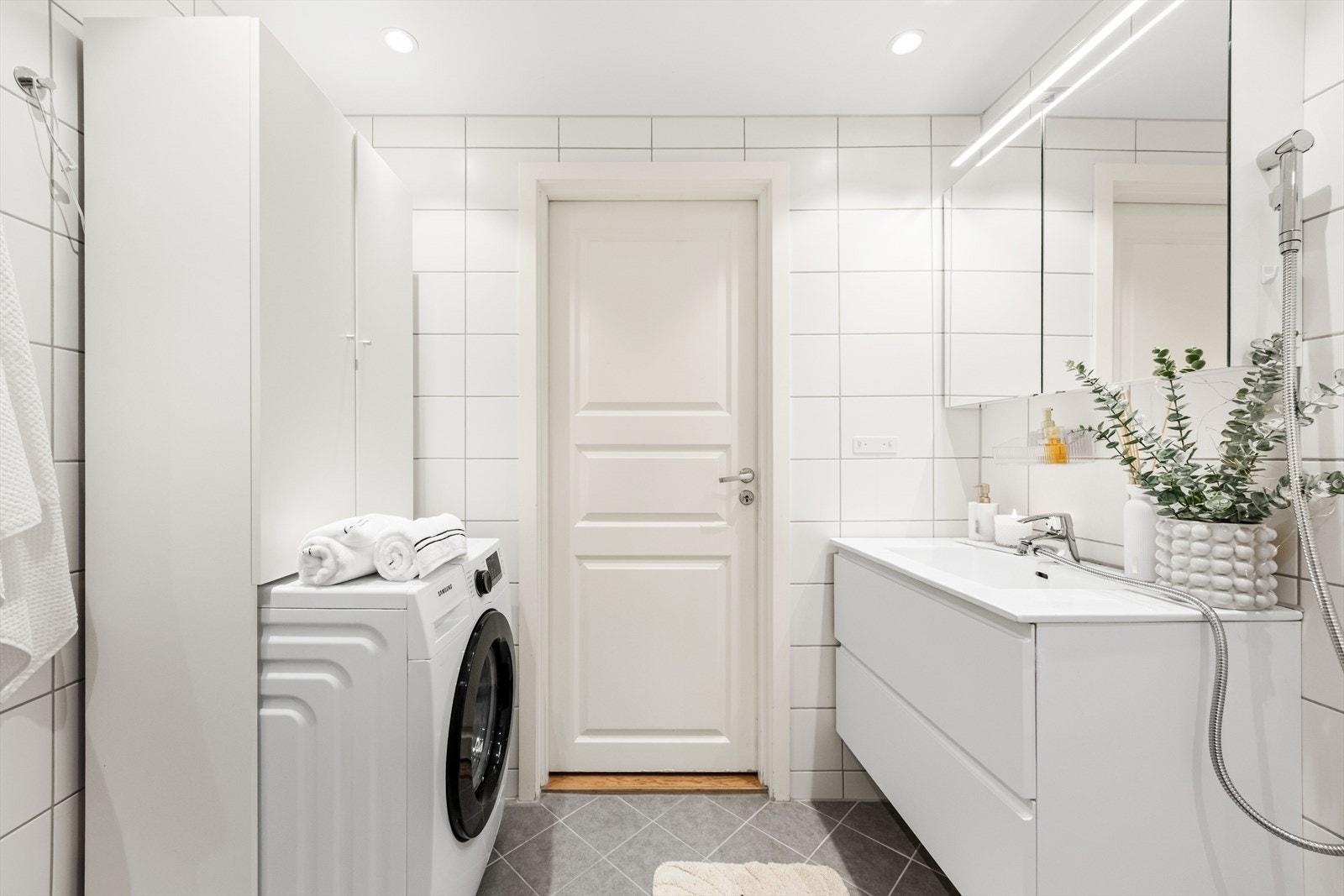 Badet er utstyrt med vegghengt toalett, hånddusj er montert, dusjhjørne med glassvegg, innredning med nedfelt servant, speilskap, samt høyskap. Det er også opplegg for vaskemaskin. Galleribilde