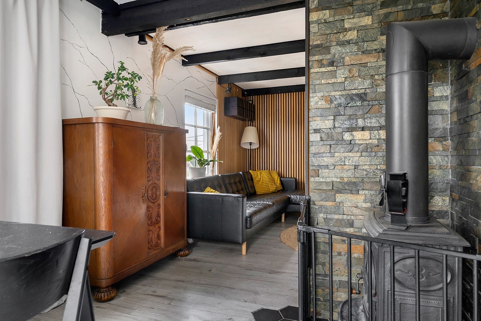 Lun stue med vedovn, synlige bjelker og hyggelig atmosfære. Galleribilde