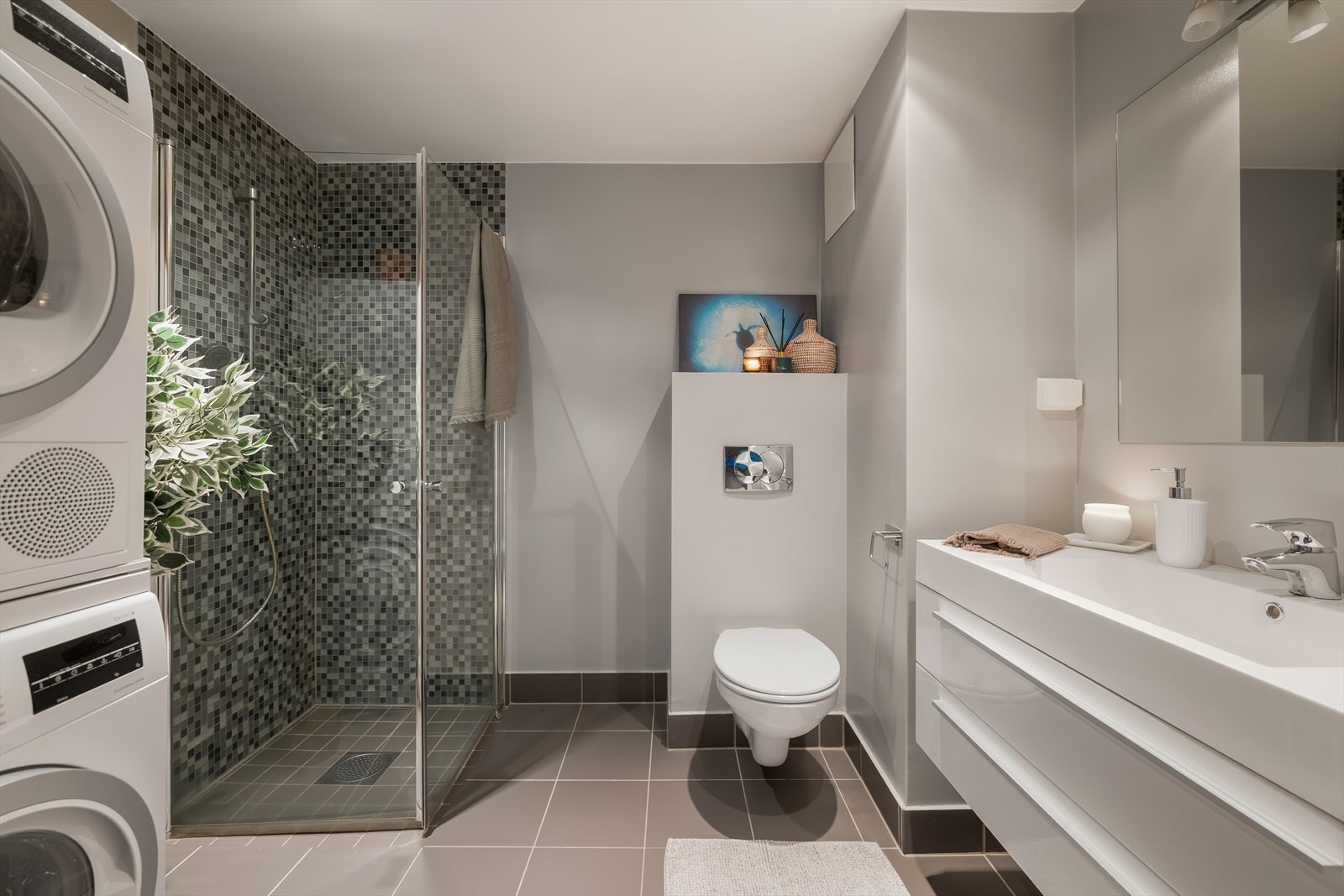 Bad nummer to er stilrent flislagt, med varme i gulvet og praktisk opplegg for vaskemaskin og tørketrommel. Galleribilde