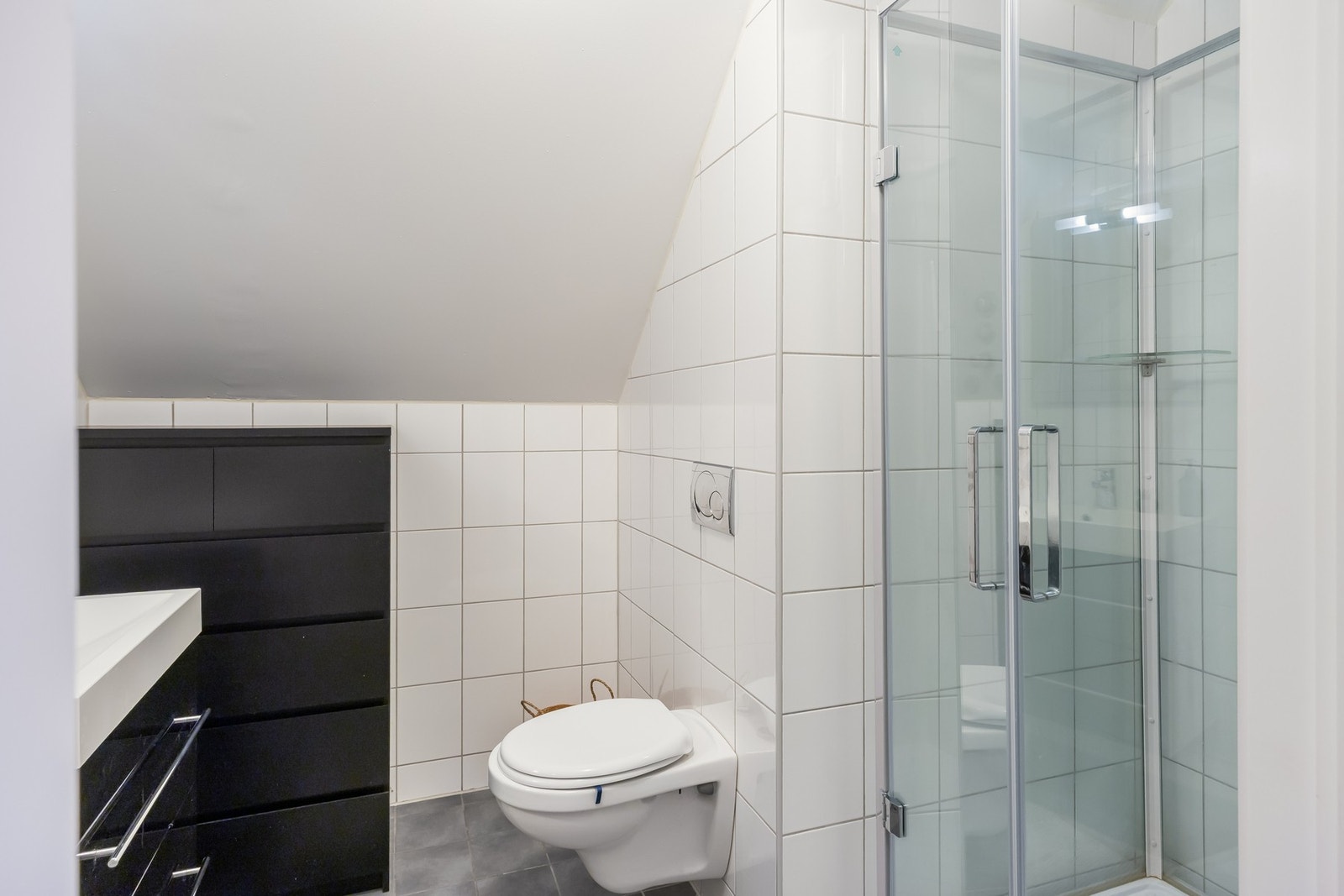 Badet er flislagt og har dusjkabinett, vegghengt wc og baderomsinnredning. Galleribilde